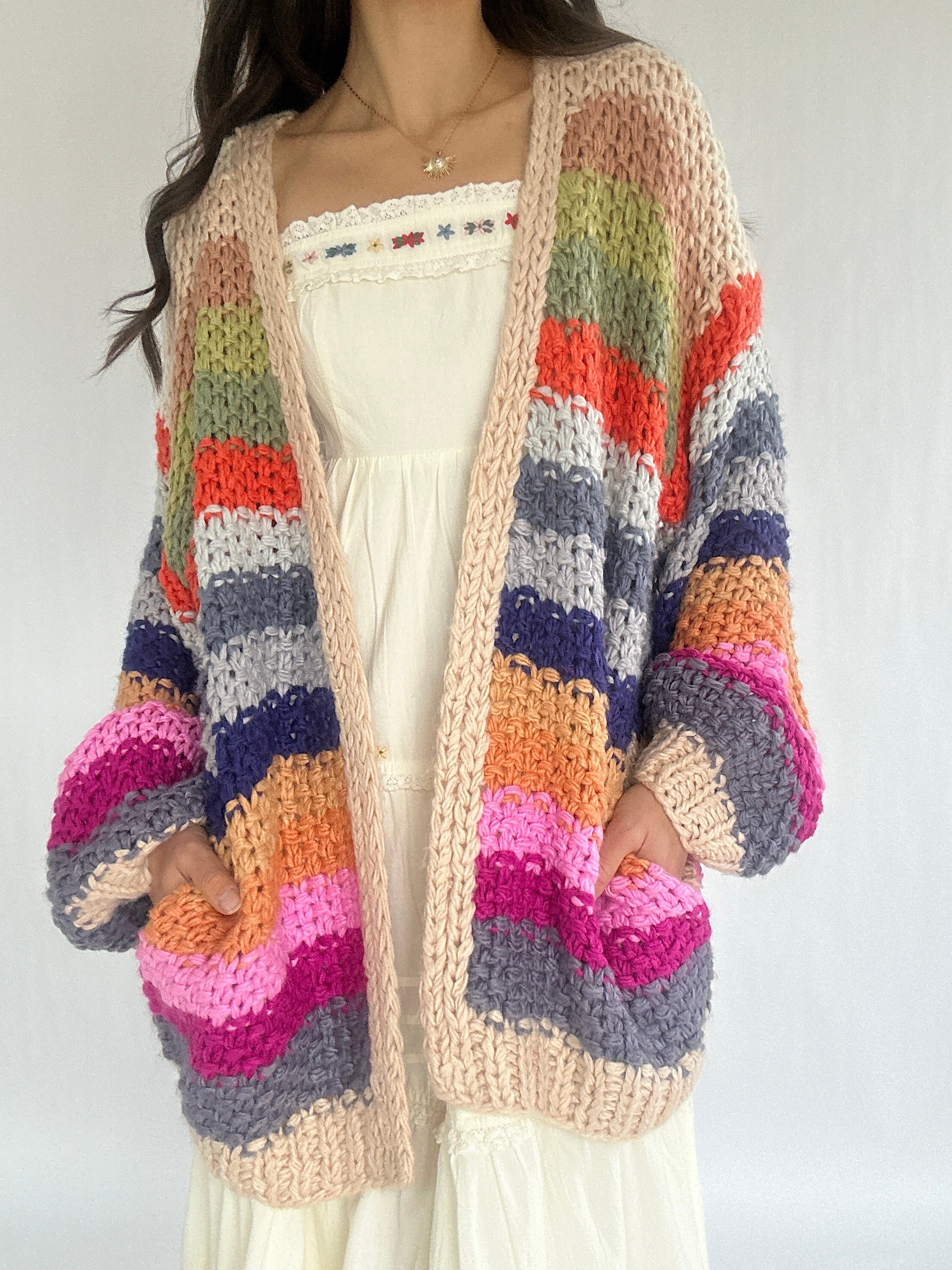 Colorful striped cardigan worn by a person on a plain background with hands in pockets