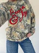 Camouflage hoodie with red text 'Peace & Love' worn by a person on a white background