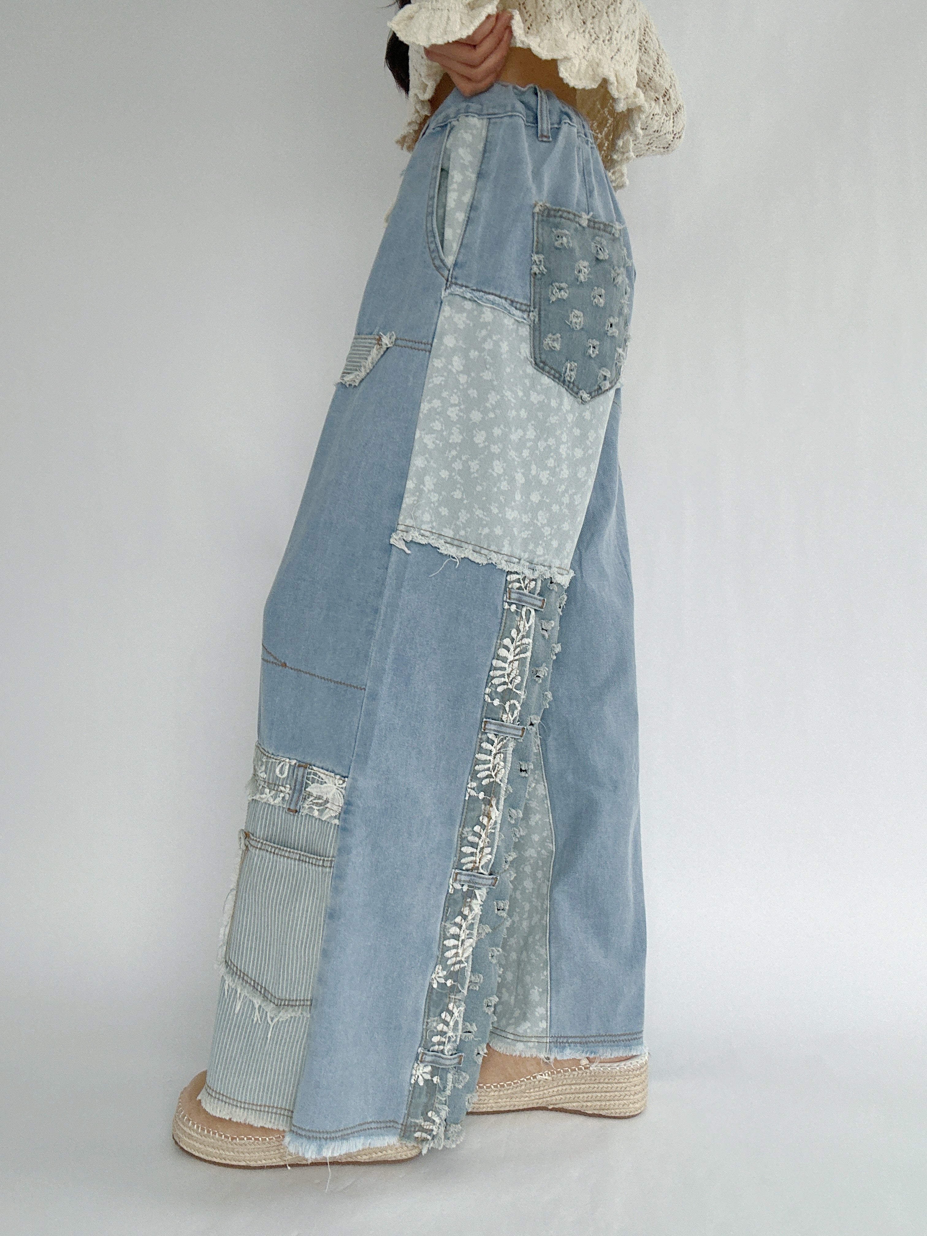 Denim patchwork pants with floral patterns on a plain background from side