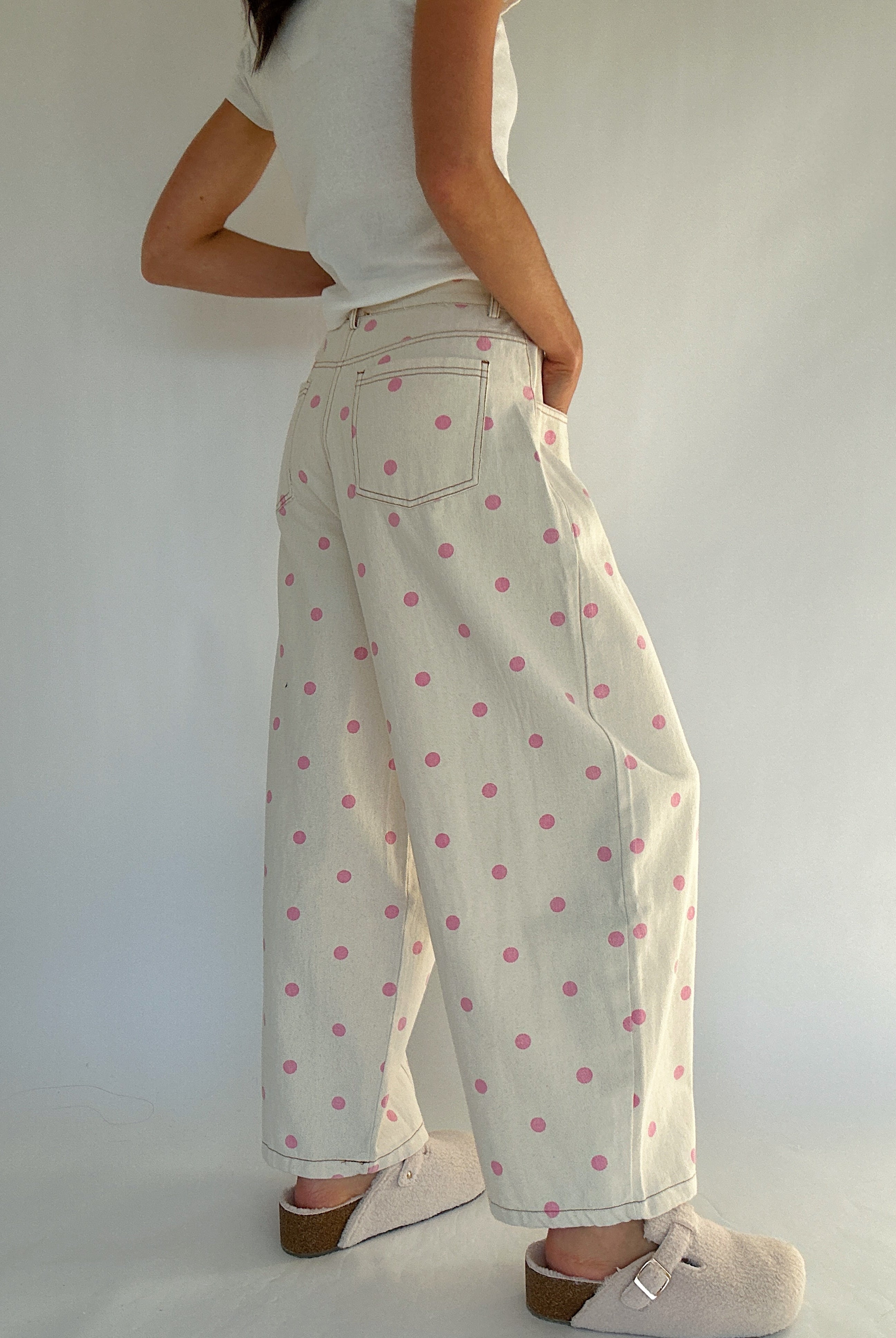 Person wearing a white top and polka dot pants against a plain background