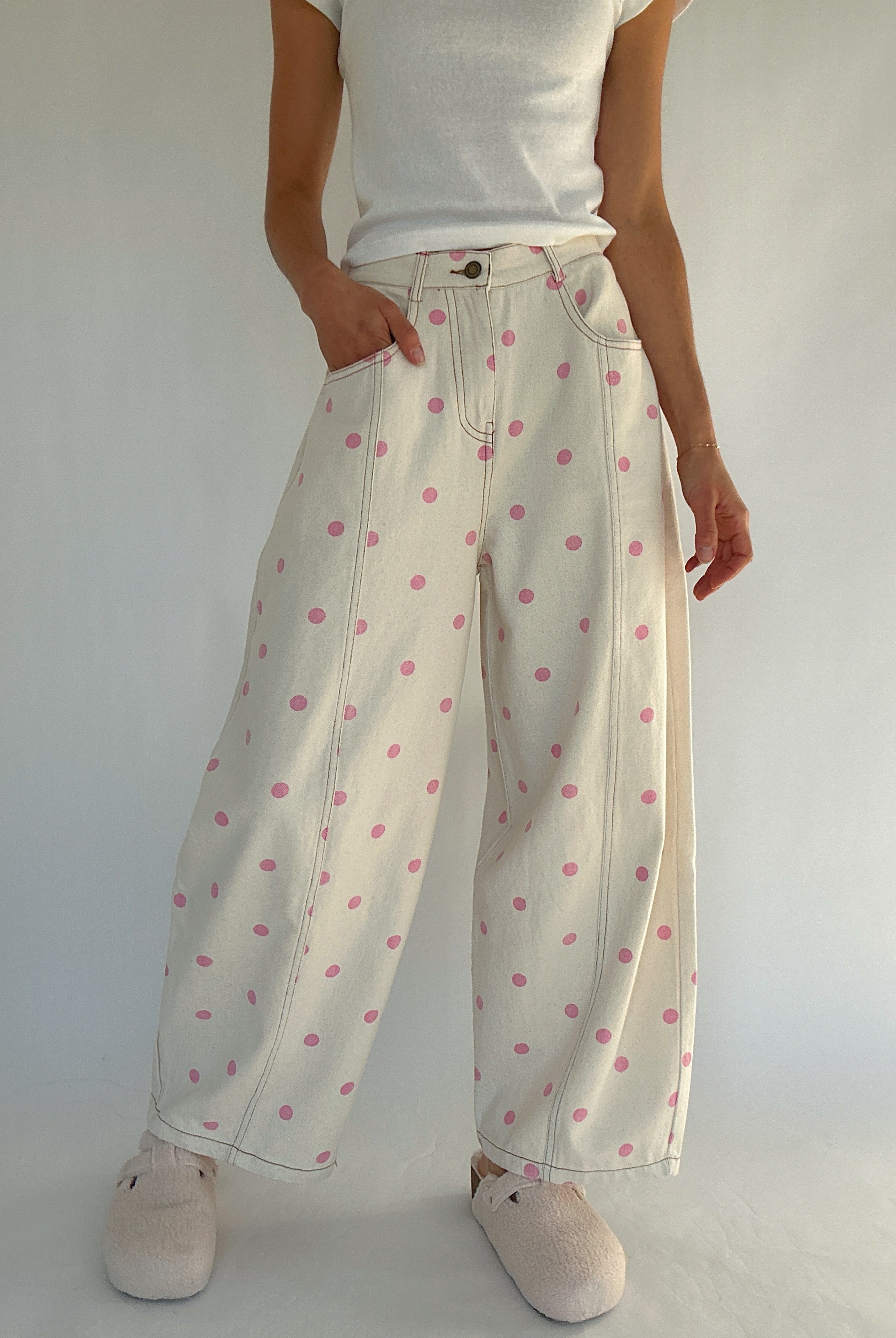Person wearing white polka dot pants on a plain background