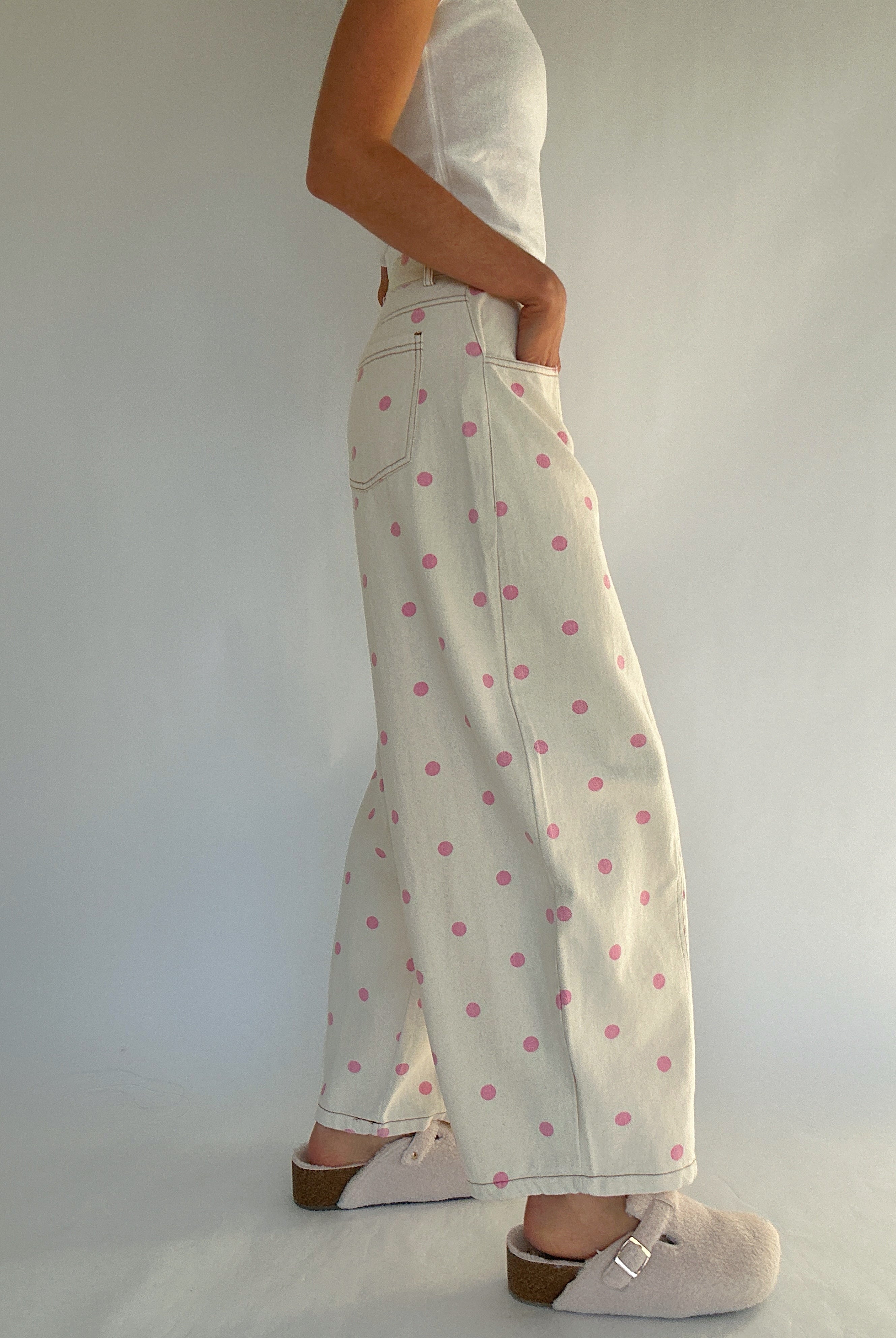 Person wearing white pants with pink polka dots against a plain background from side