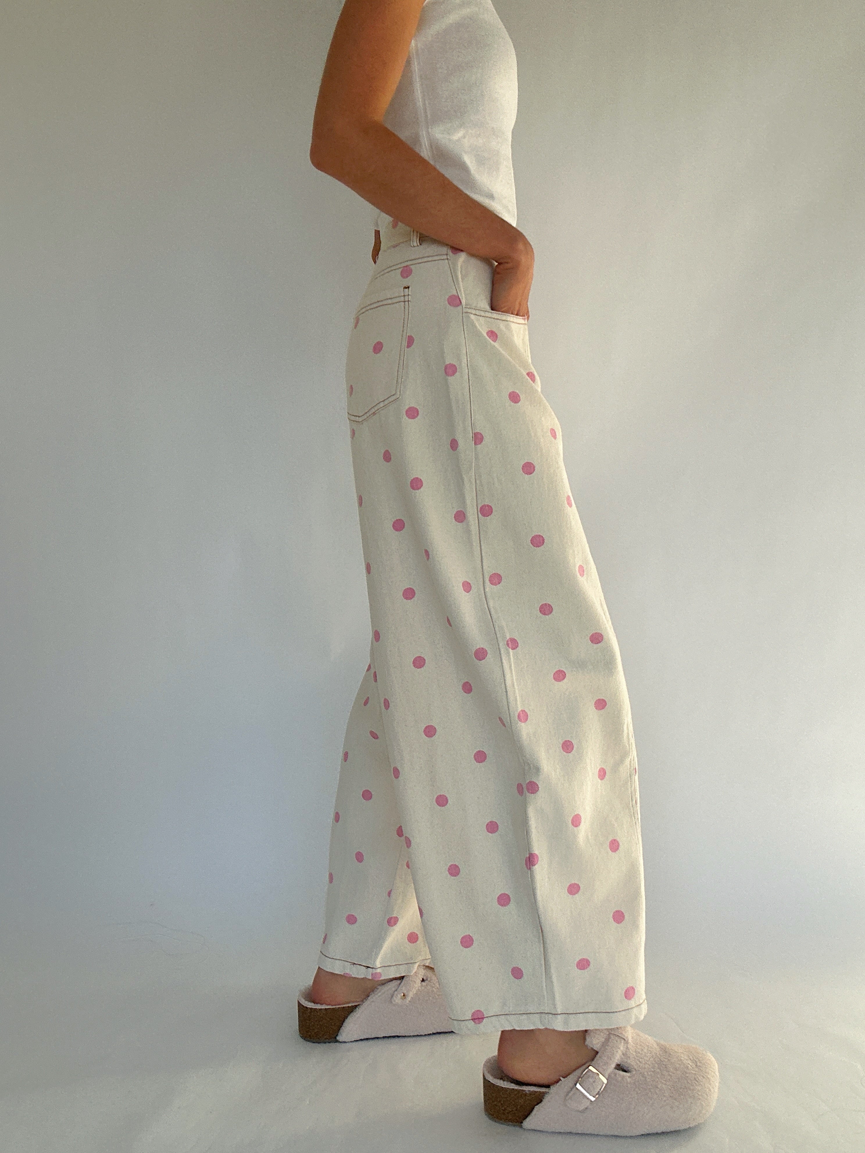 Person wearing white pants with pink polka dots against a plain background from side