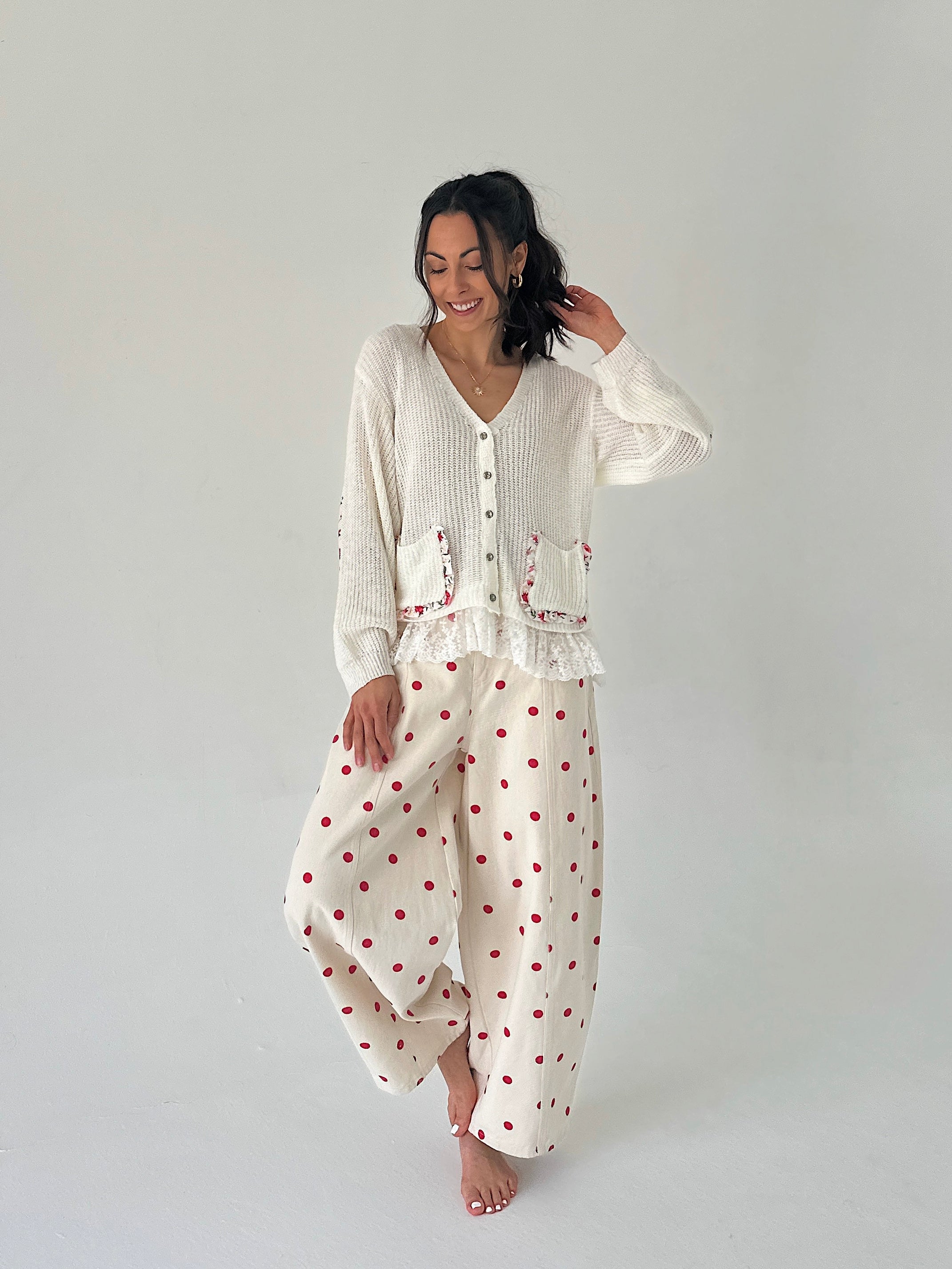 Woman wearing a white outfit with red polka dots on a plain background