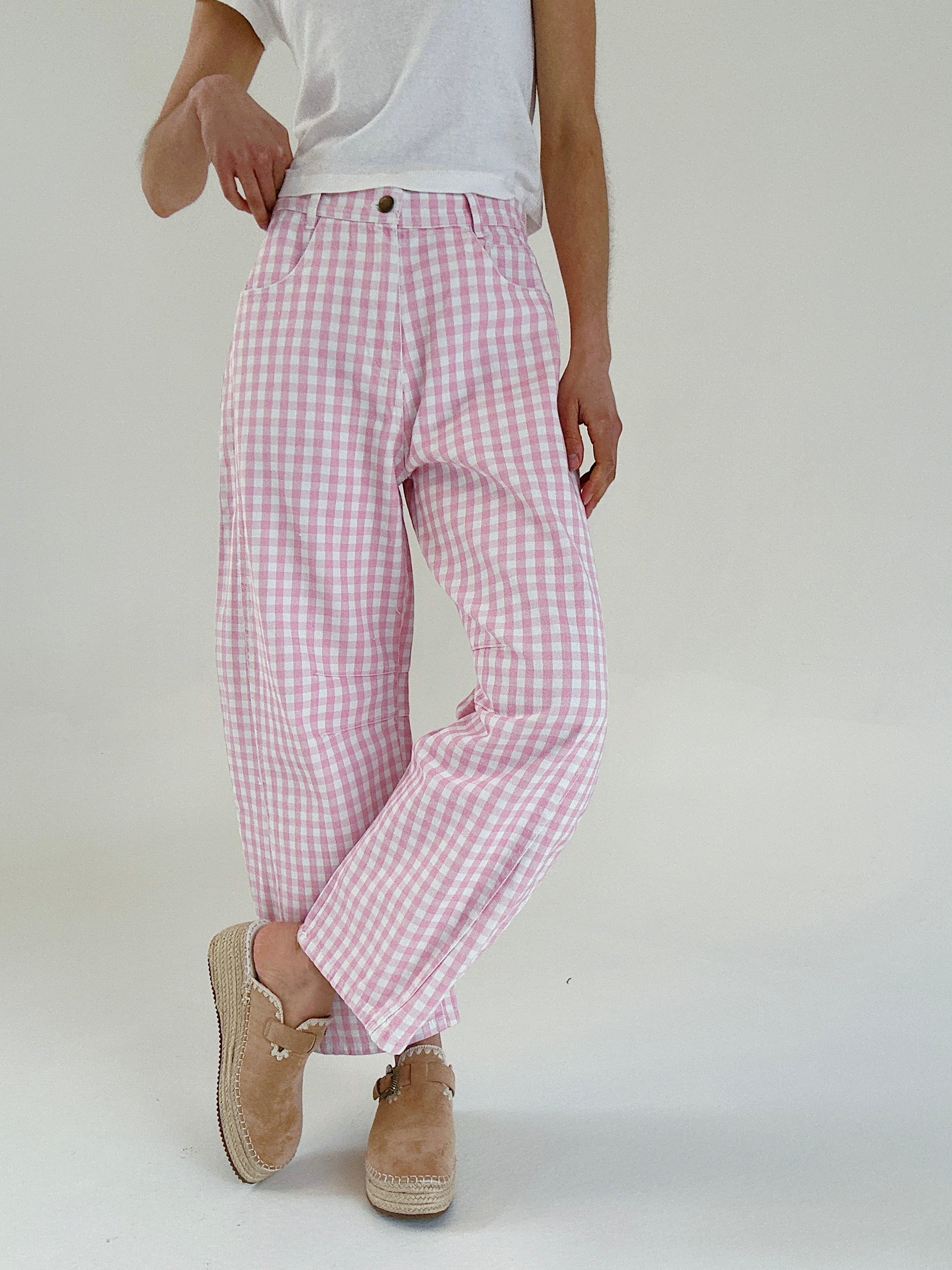 Person wearing pink checkered pants and white shirt on a plain background