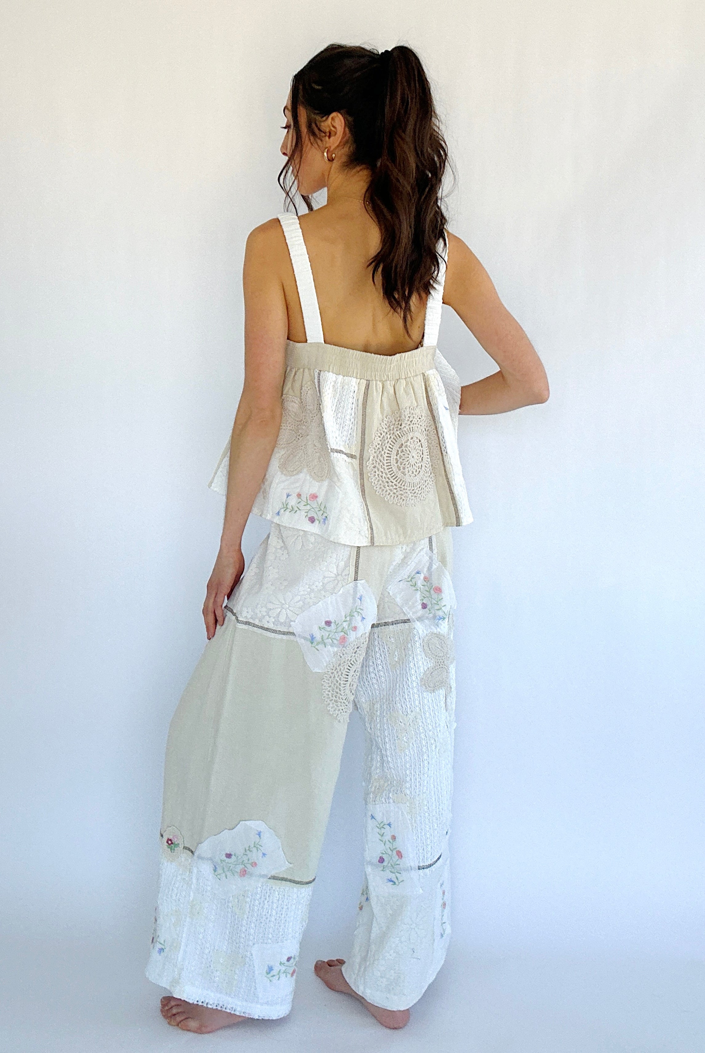 Woman wearing a beige floral top with matching wide-leg pants against a white background from back