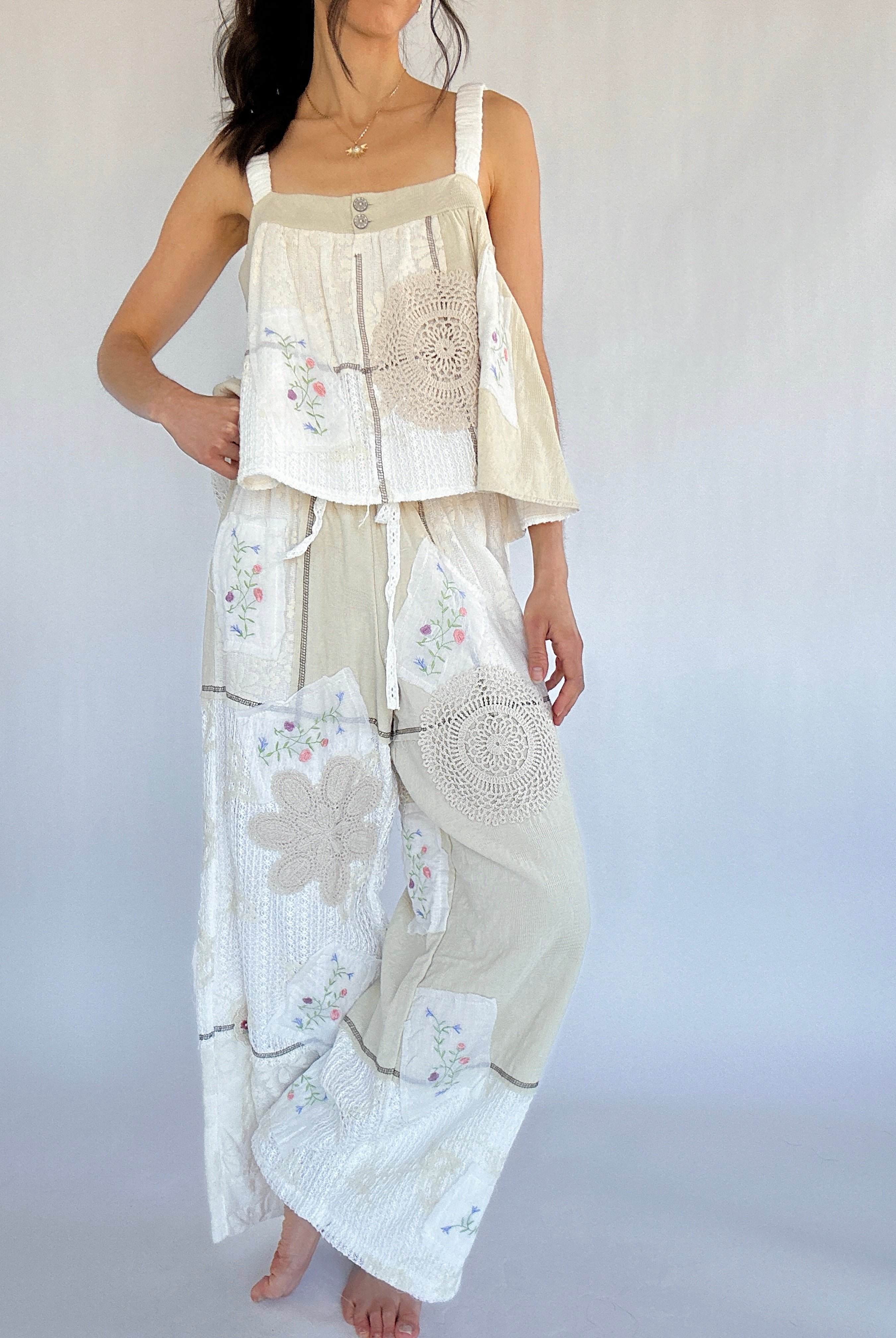 Woman wearing a white and beige outfit with floral patterns on a plain background