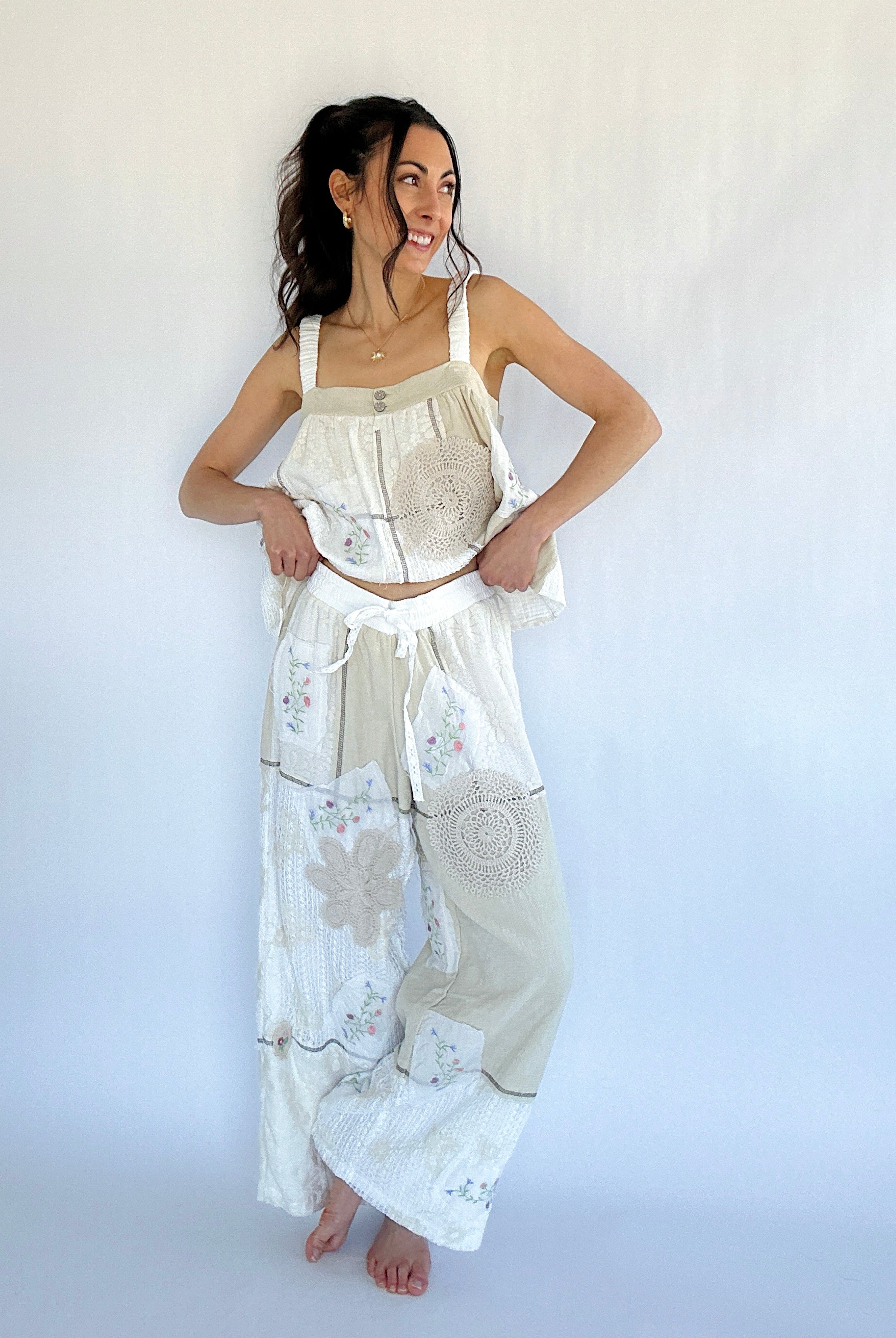 Woman wearing a white embroidered top and matching pants against a white background