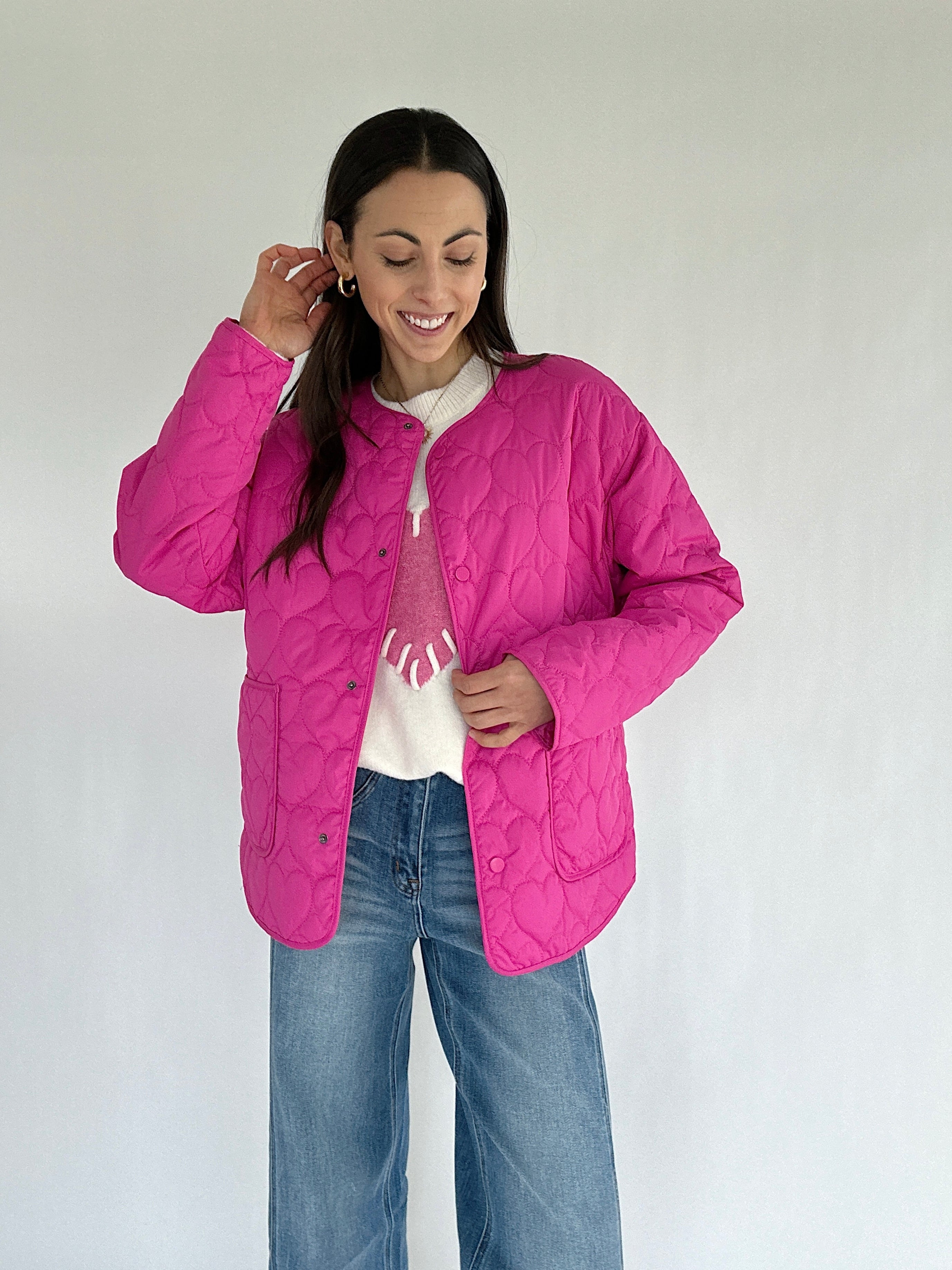 Woman wearing a pink quilted jacket on a plain background