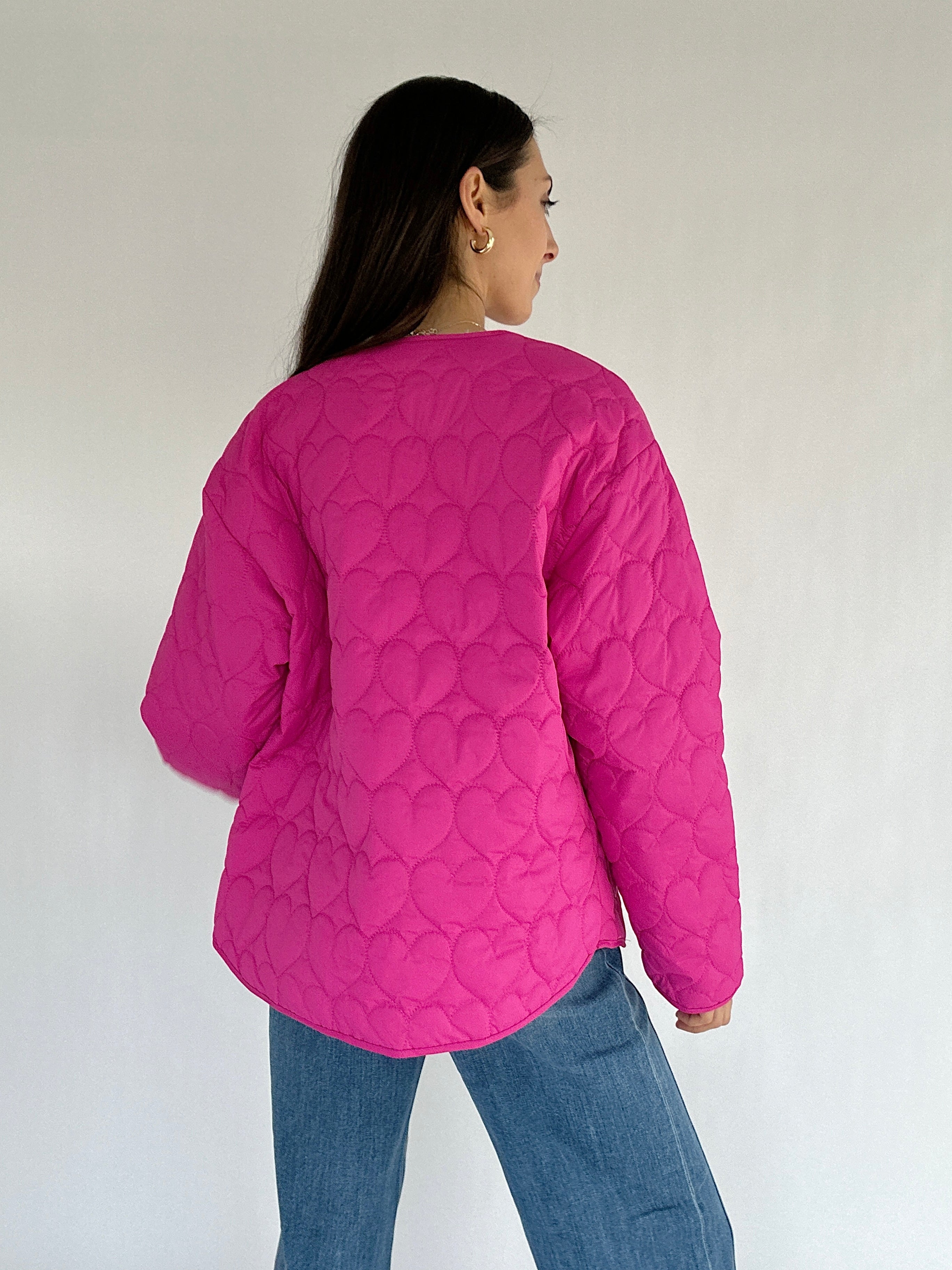 Person wearing a pink quilted jacket against a white background