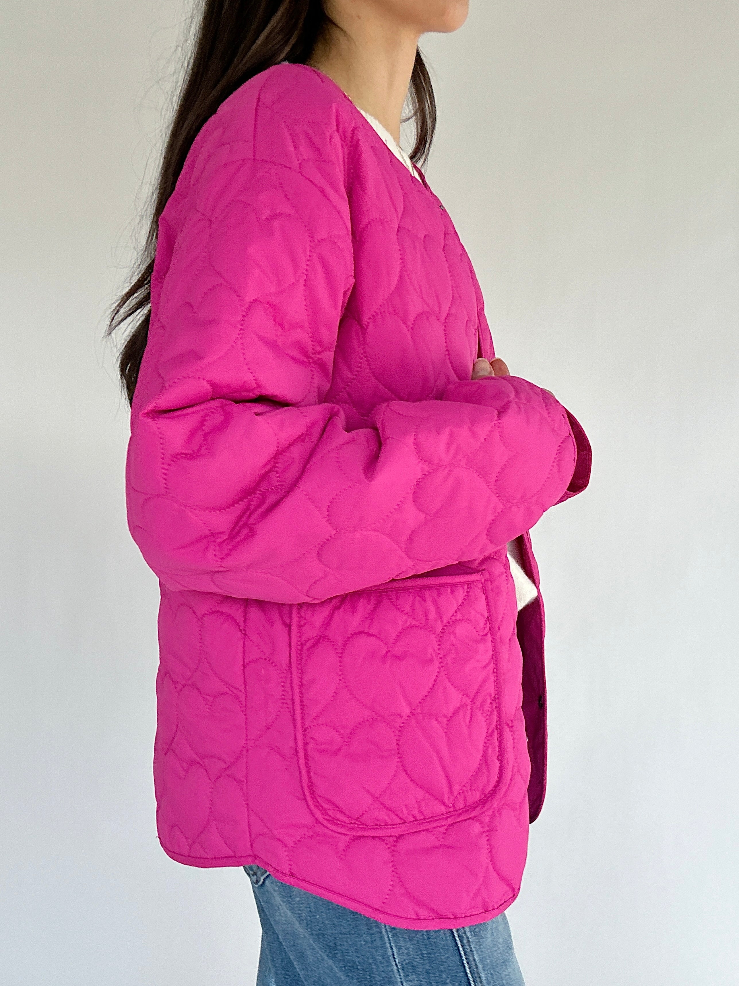 Person wearing a pink quilted jacket against a plain background showing side pocket