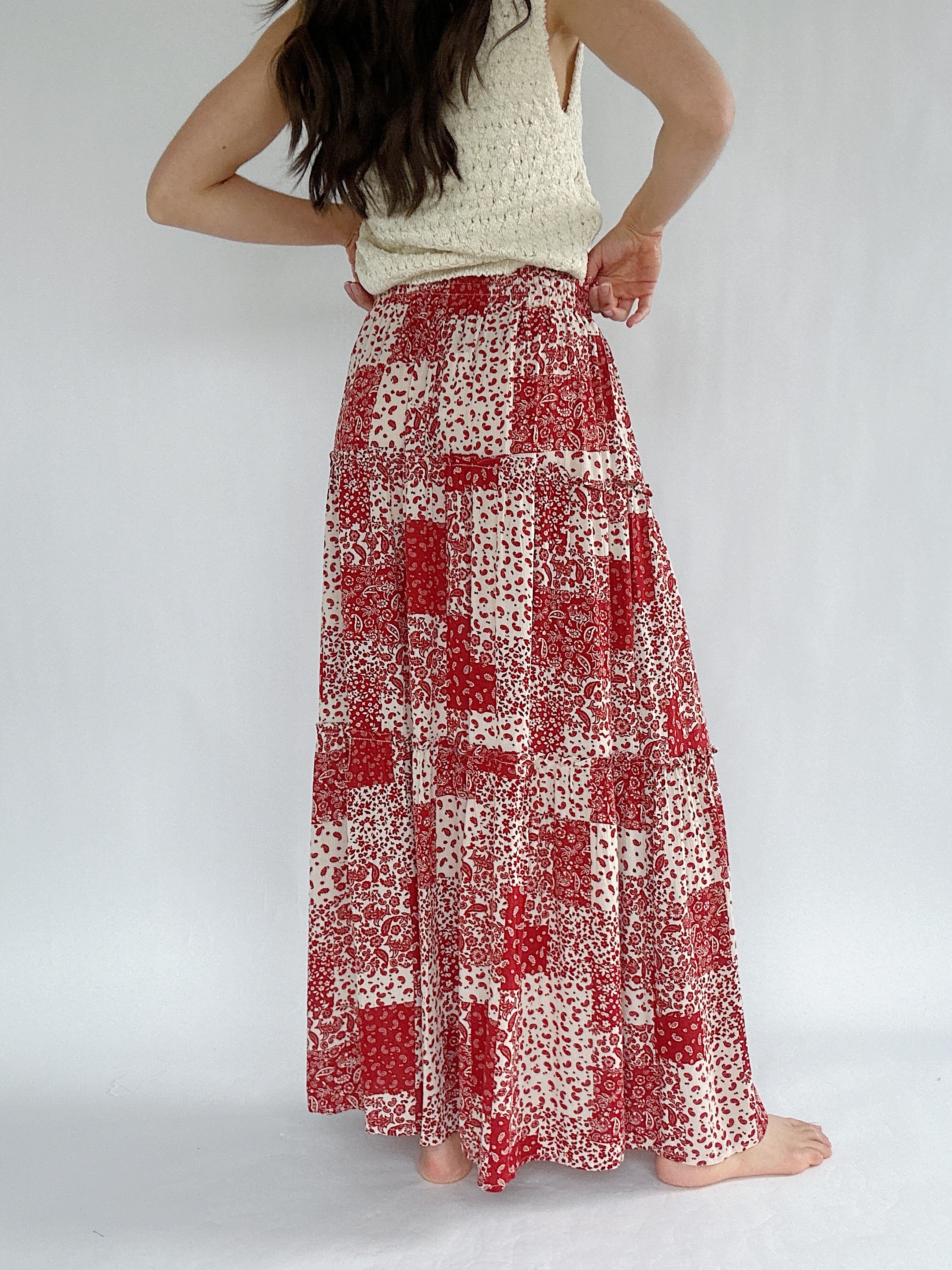 Person wearing a red and white patterned skirt on a plain background - back of skirt