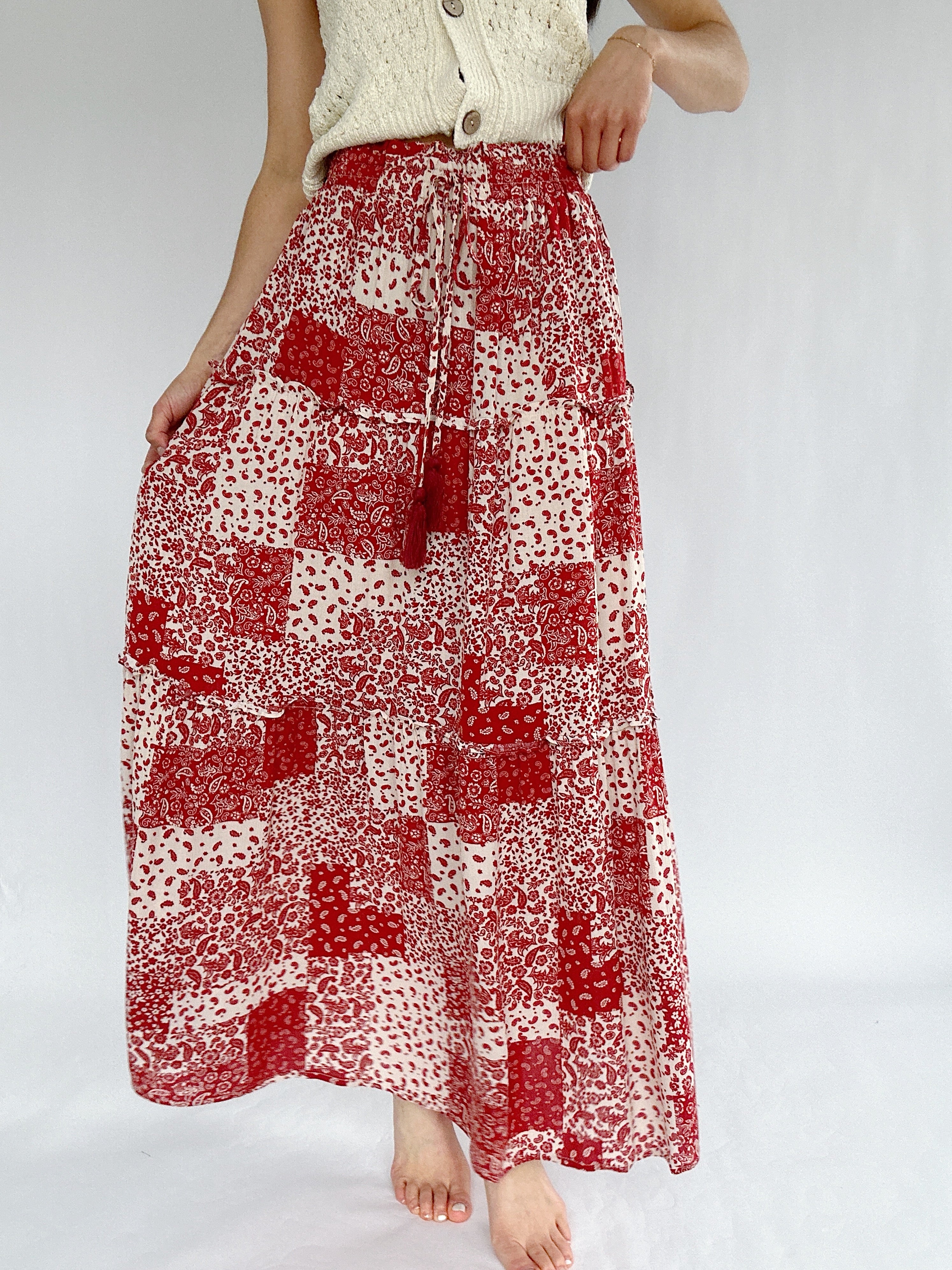 Red and white patterned skirt worn by a person on a plain background