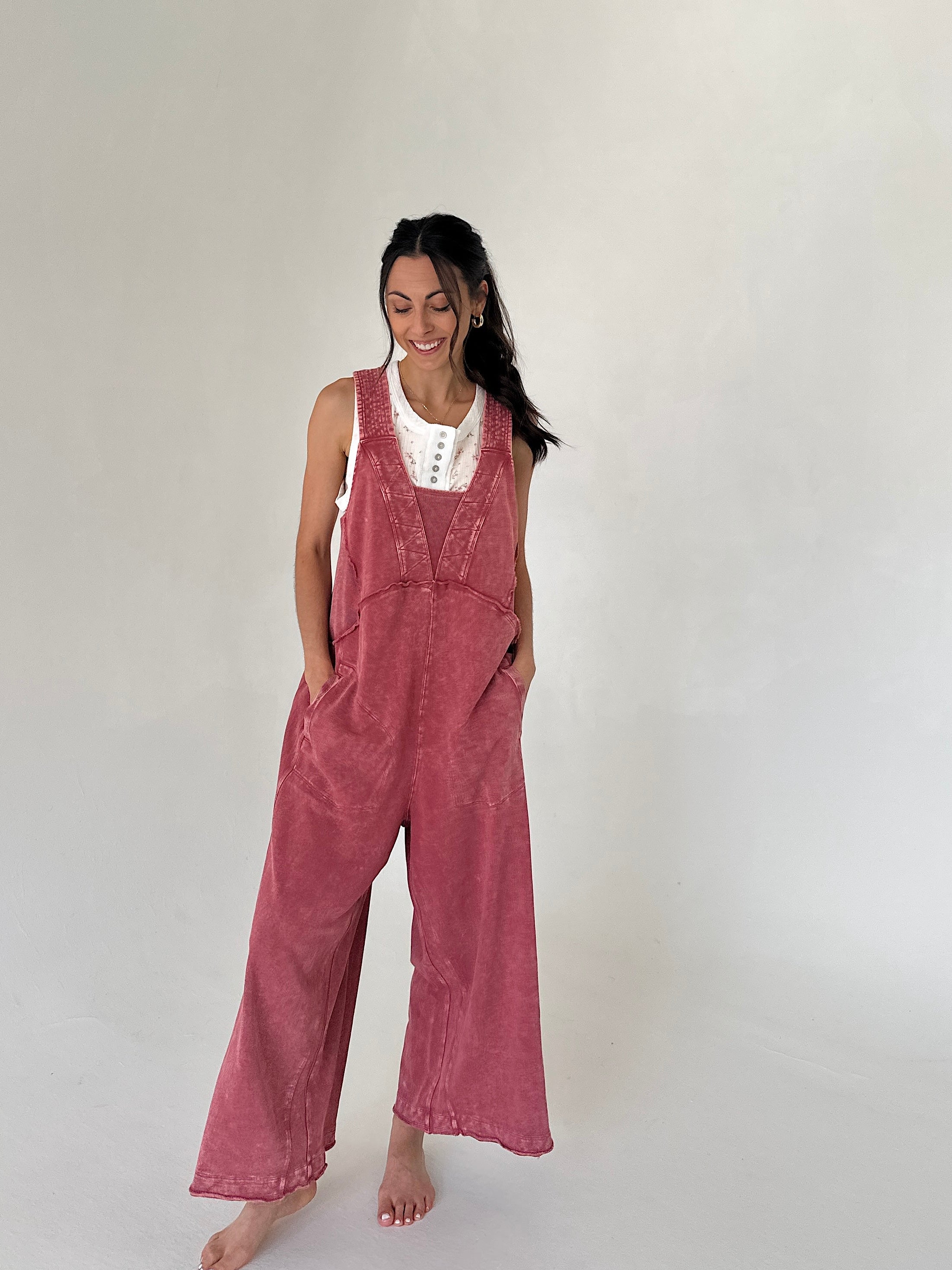 Woman wearing pink terry knit overalls on a plain background
