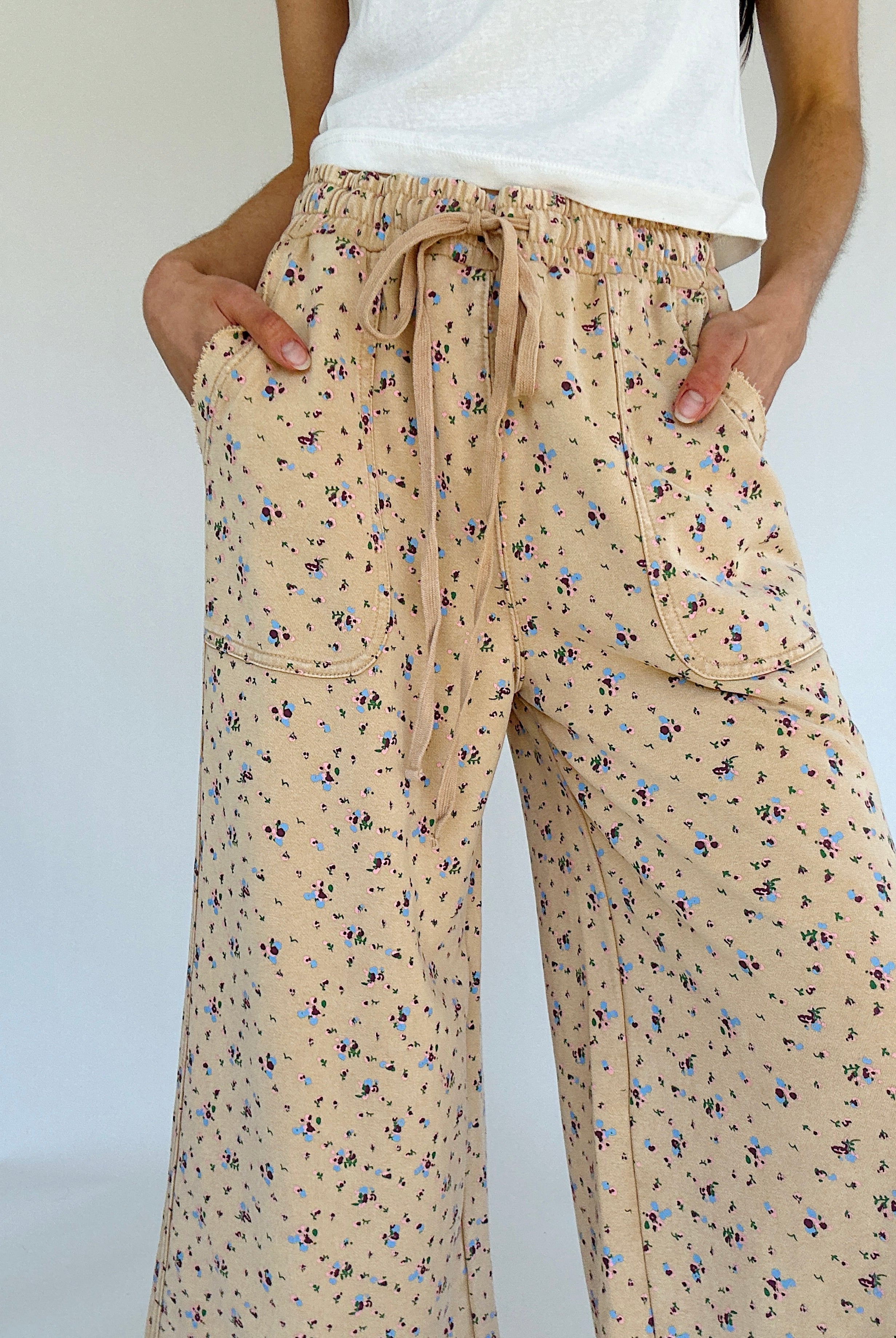 Beige floral pants worn by a person on a white background