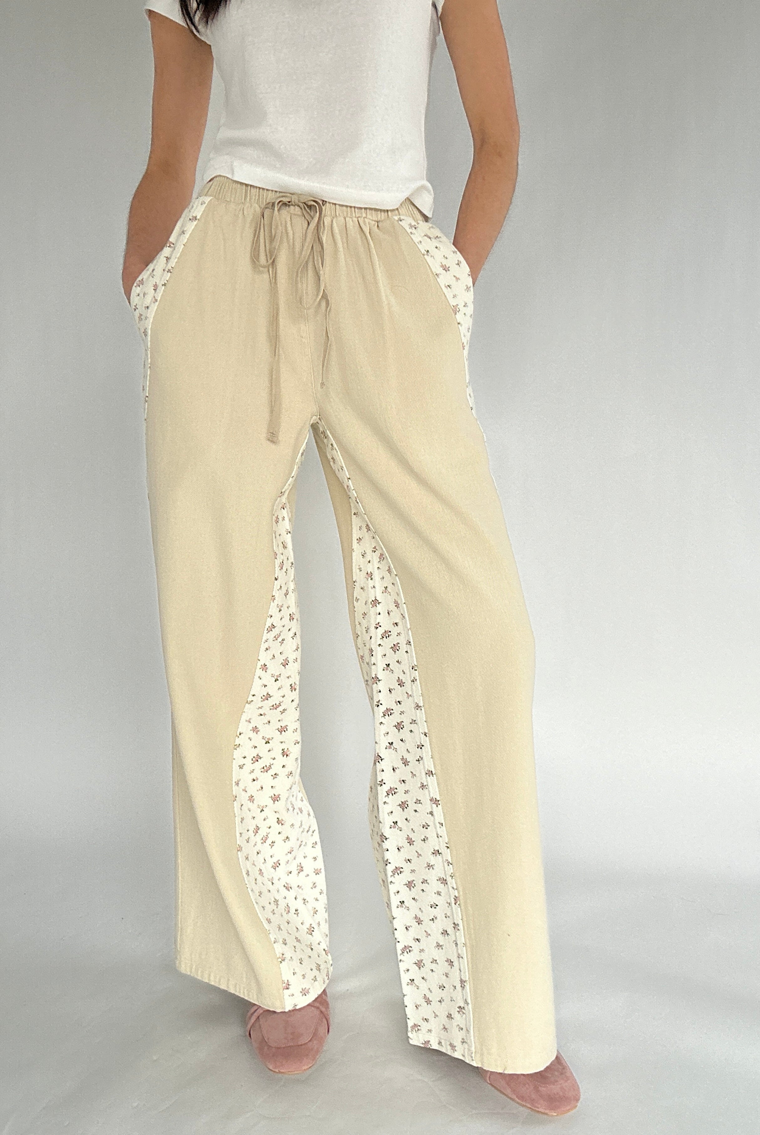 Beige pants with floral detailing on a plain background