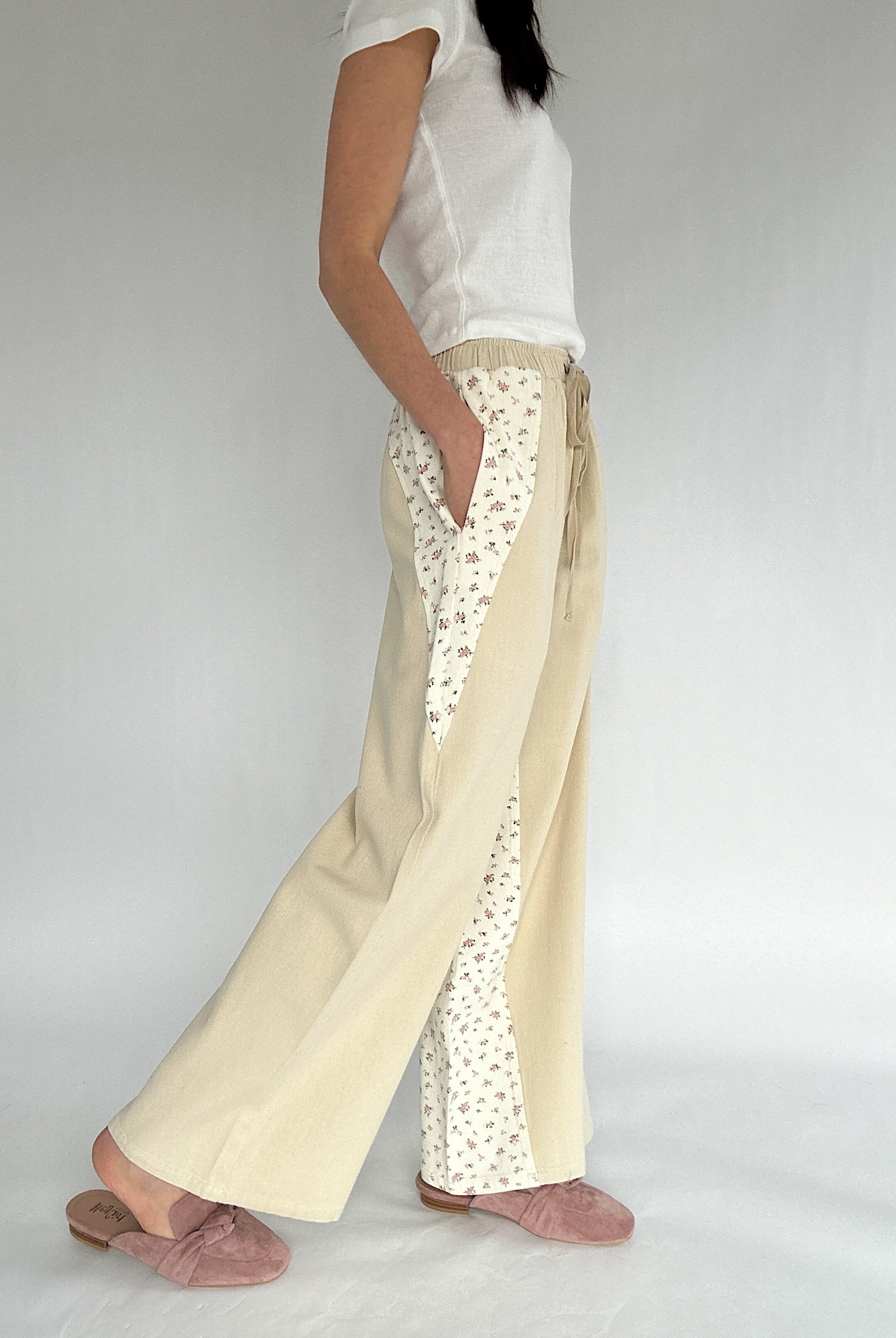 Person wearing beige pants with floral pattern on a plain background showing side with pockets