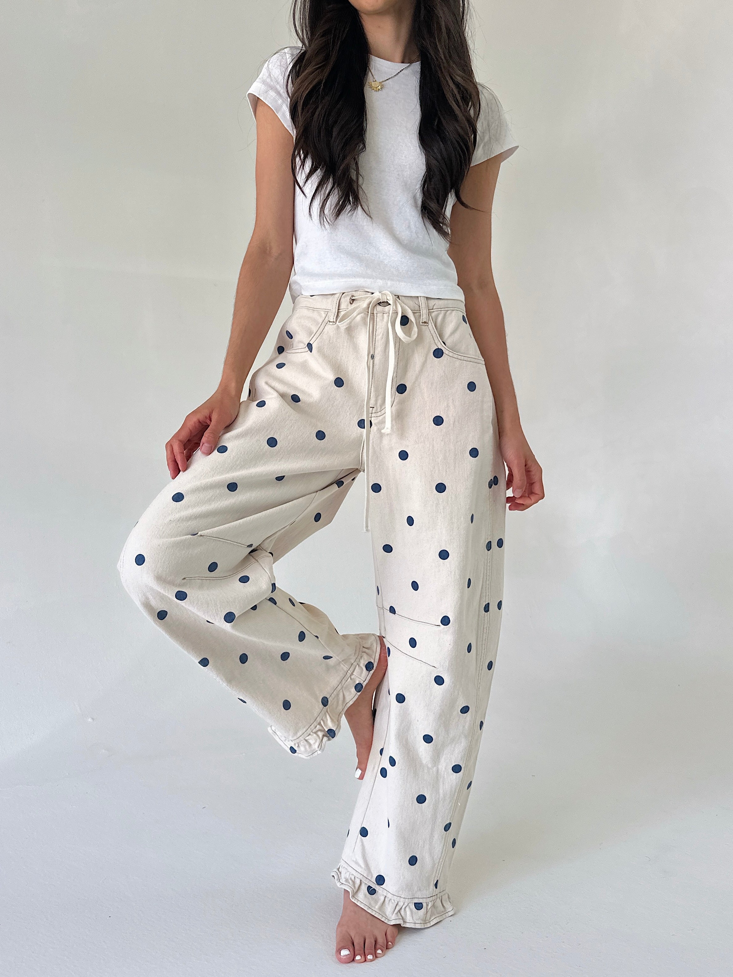 Woman wearing a white t-shirt and polka dot pants on a plain background