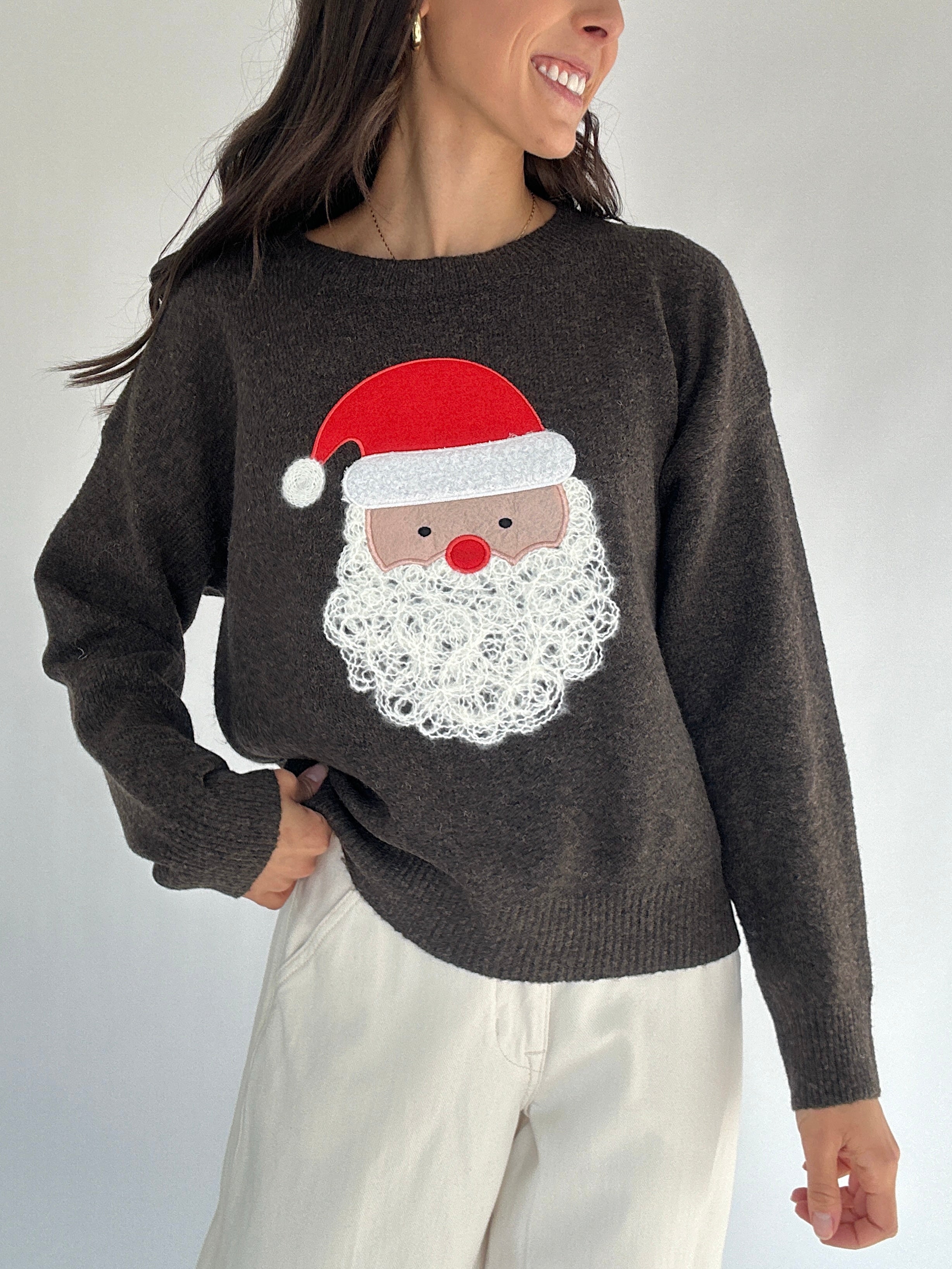 Person wearing a dark brown sweater with a Santa Claus face design on a plain background
