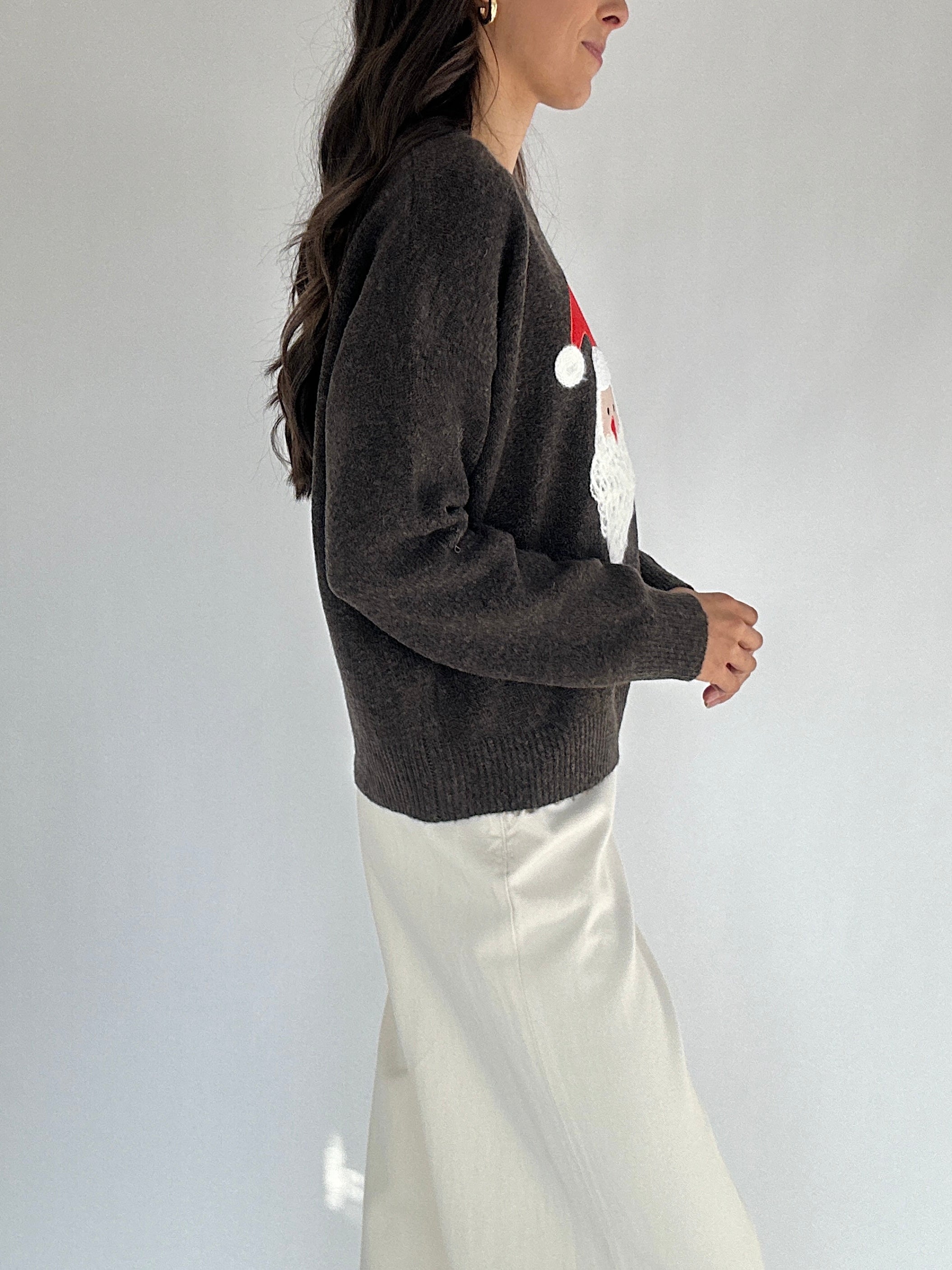 Person wearing a dark brown sweater with a colorful design on a plain background