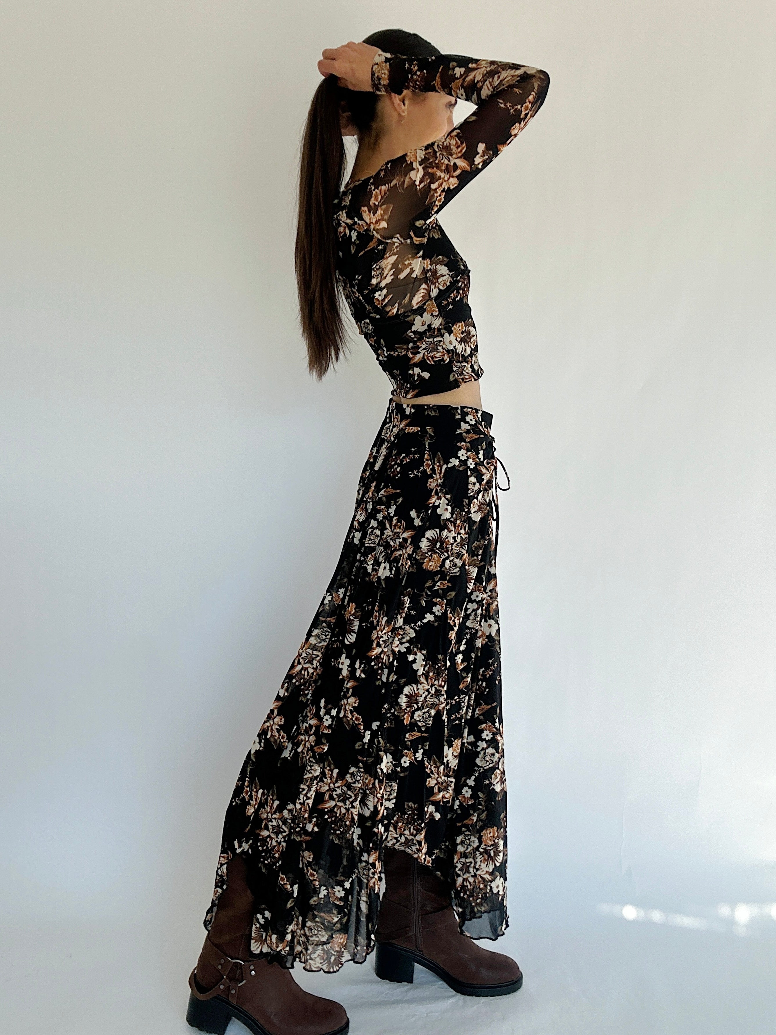 Woman wearing a black floral matching outfit with brown shoes on a white background from side view