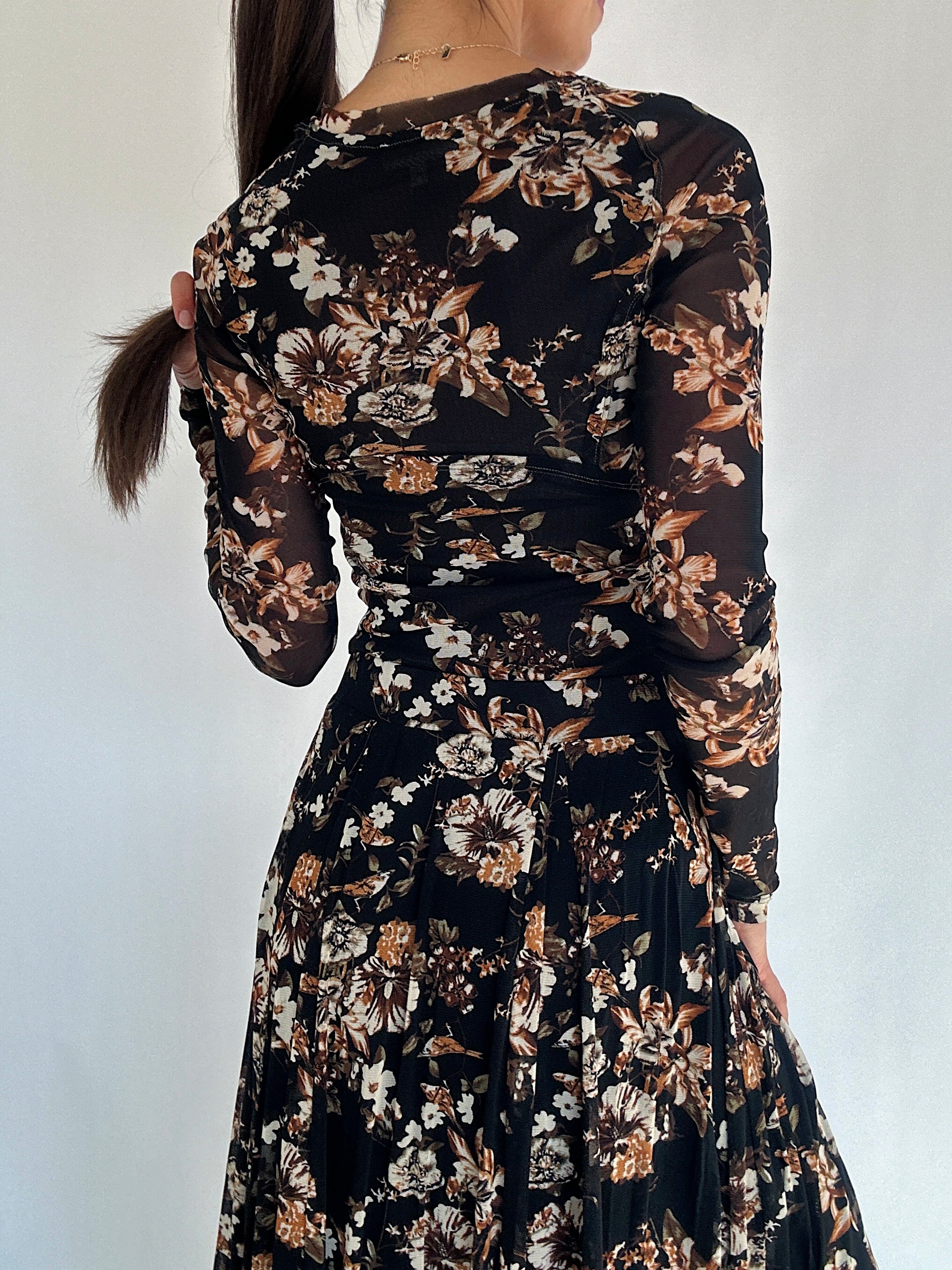 Black floral long sleeve top worn by a person against a white background showing back