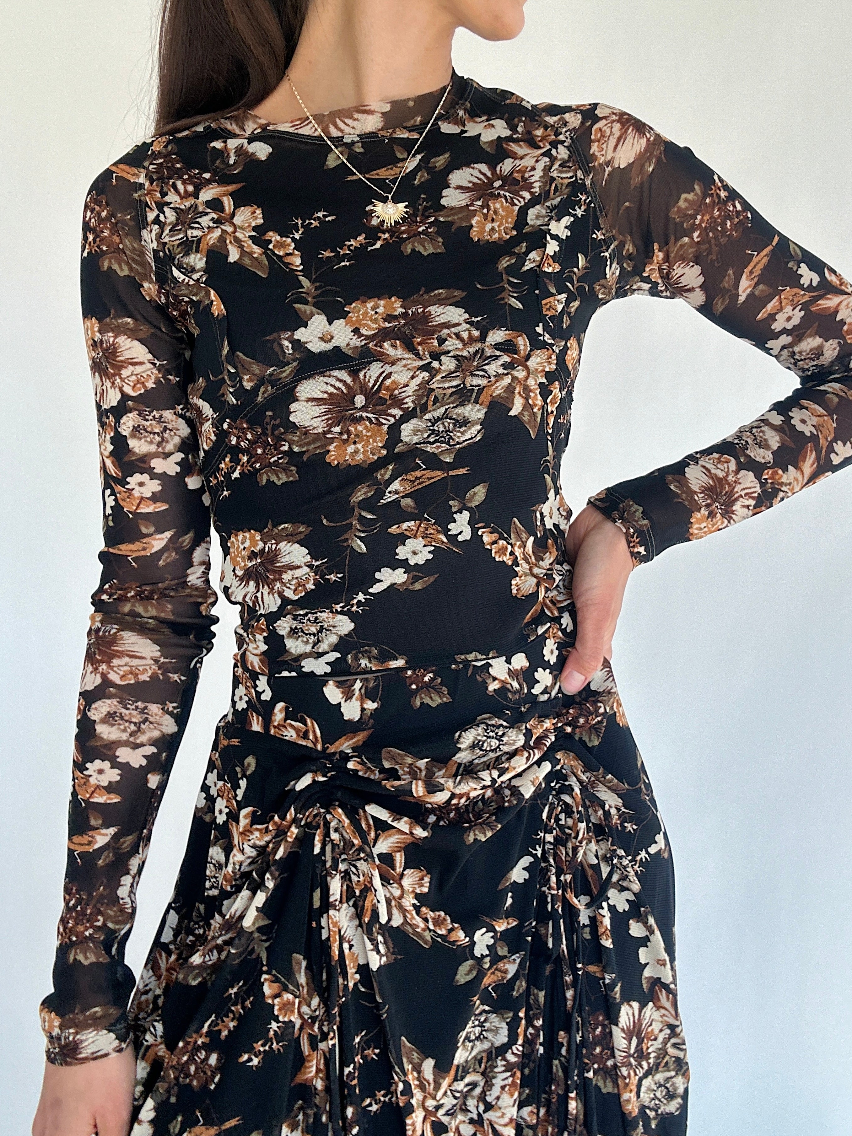 Woman wearing a black floral long sleeve top with matching skirt against a white background
