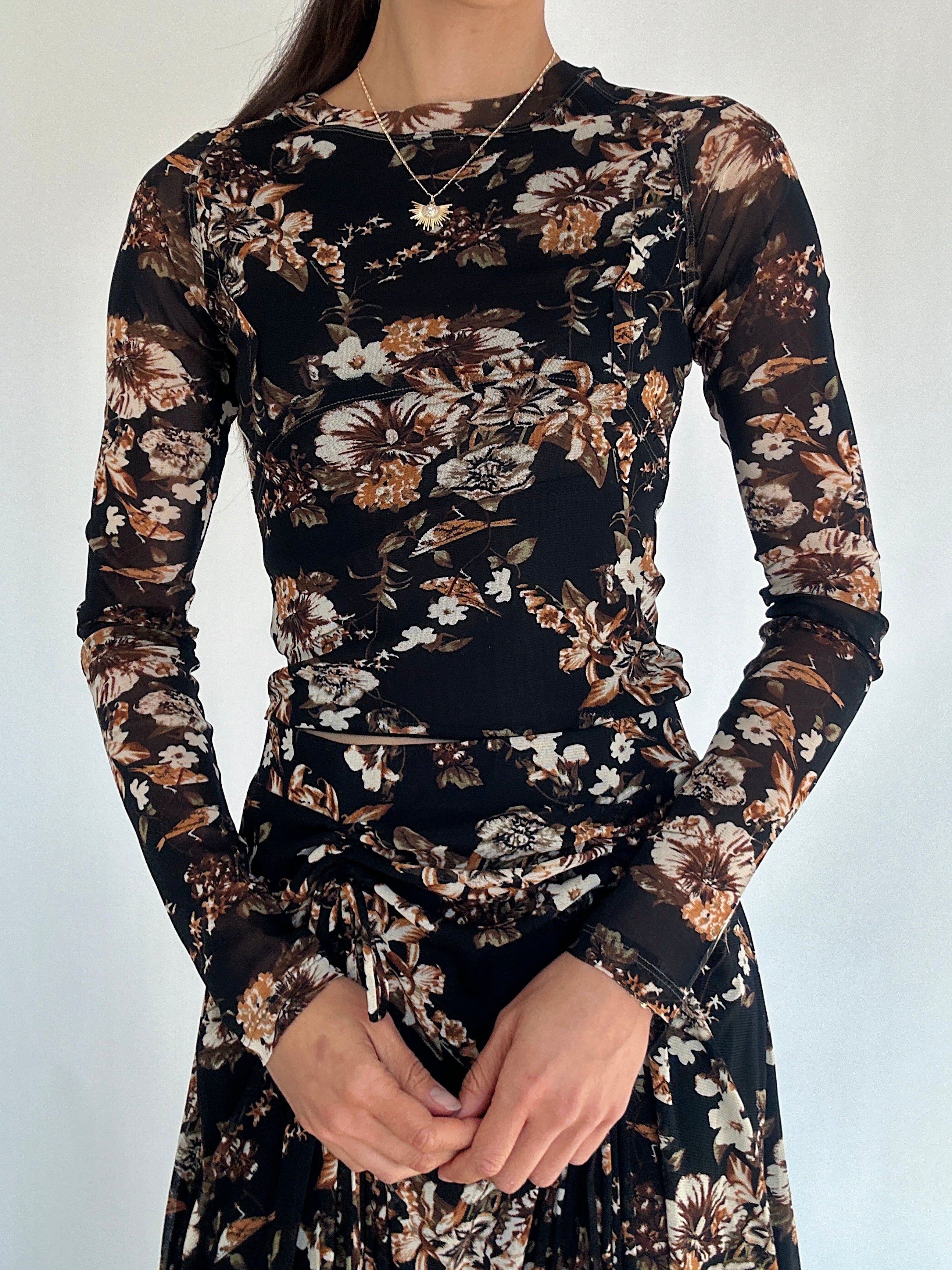 Floral patterned long sleeve top and matching skirt worn by a person on a plain background showing up close