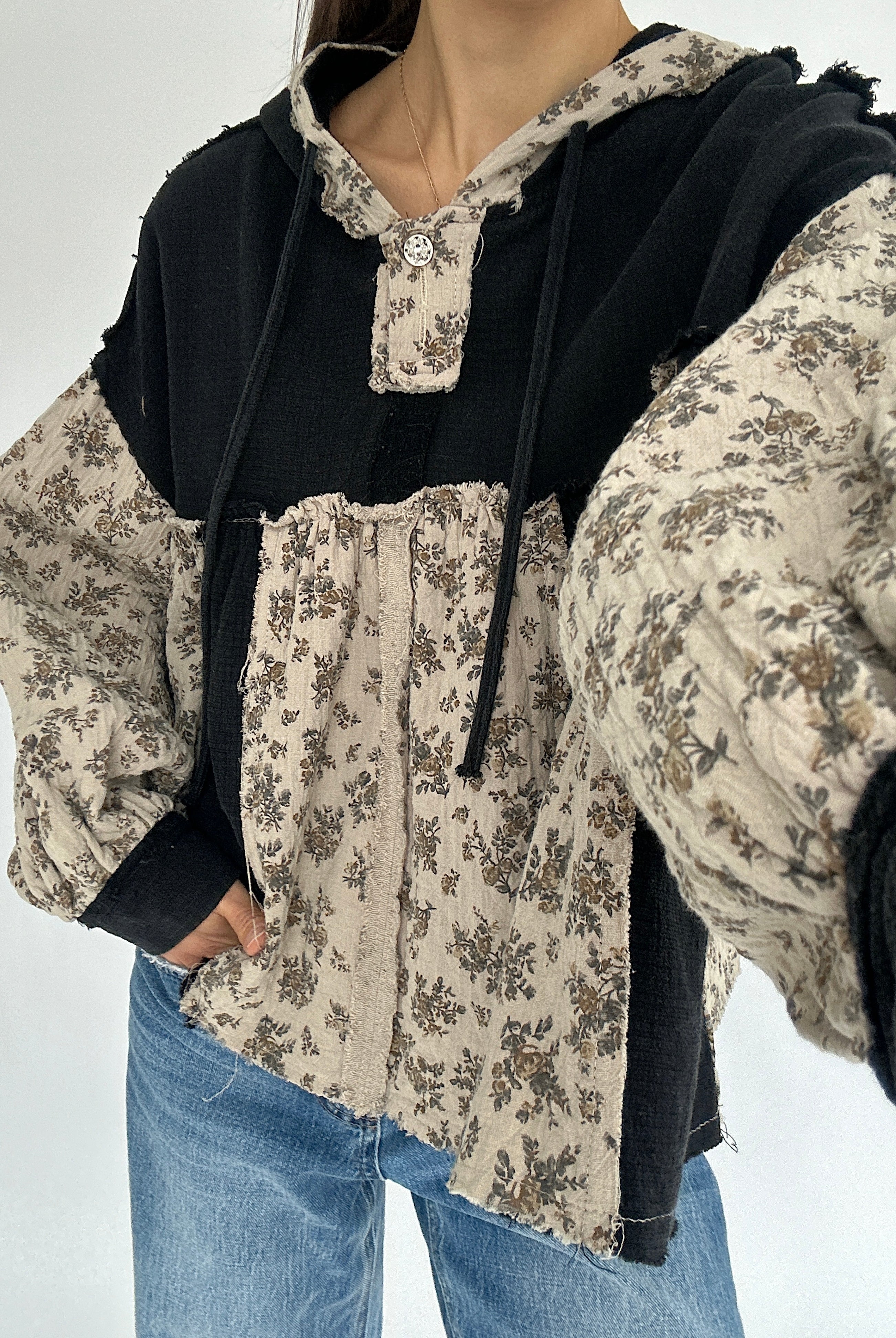 Floral patterned shirt with black hood on a plain background