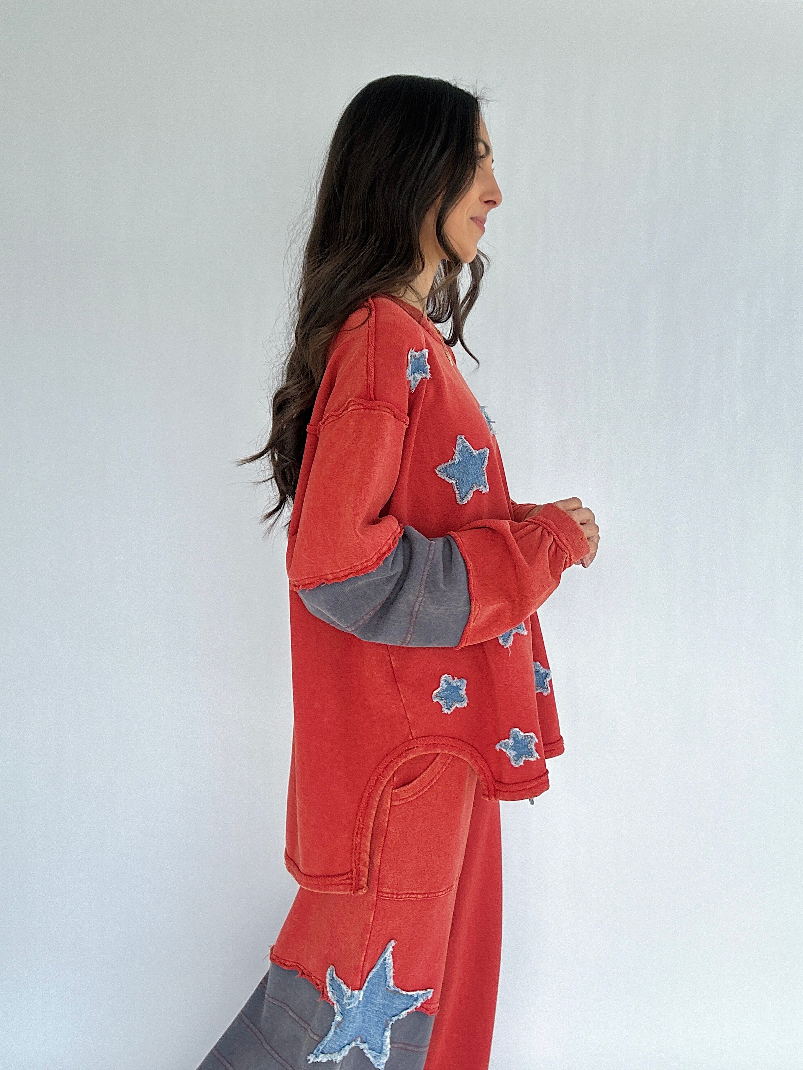 Woman wearing a red outfit with star patches on a white background showing side