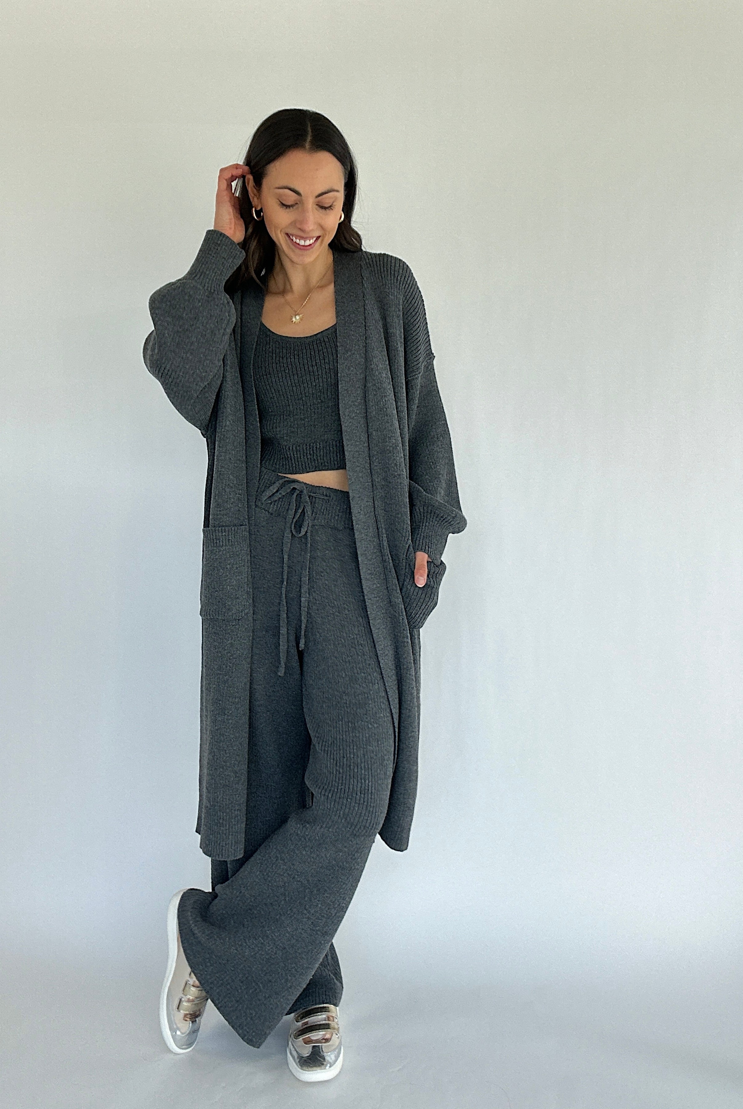 Woman wearing a gray knit outfit with a long cardigan on a white background