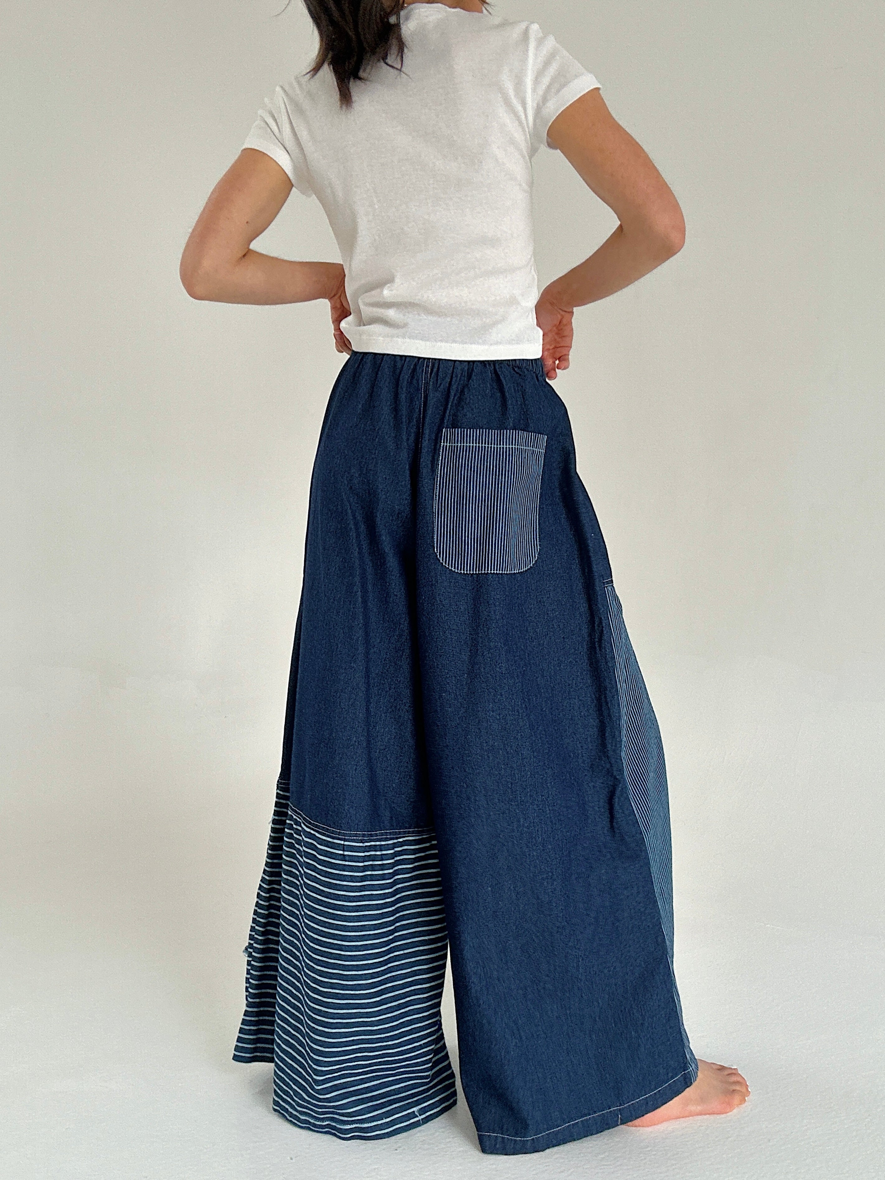 Person wearing a white t-shirt and blue denim wide-leg pants with a back pocket on a white background