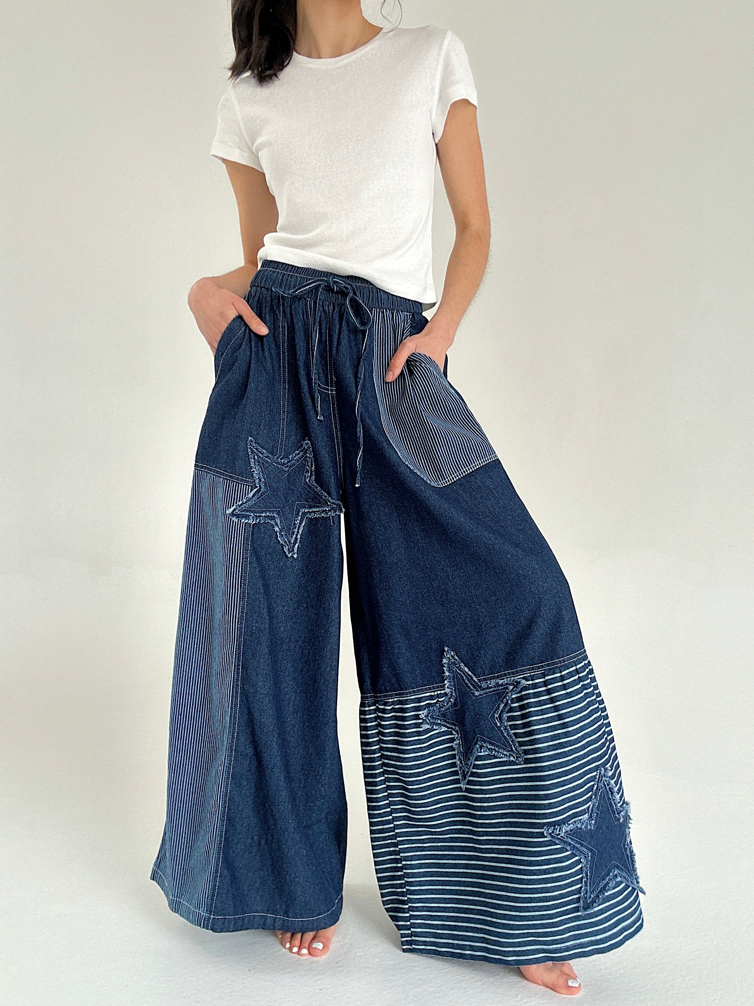Person wearing blue denim wide leg pants with star patterns on a white background