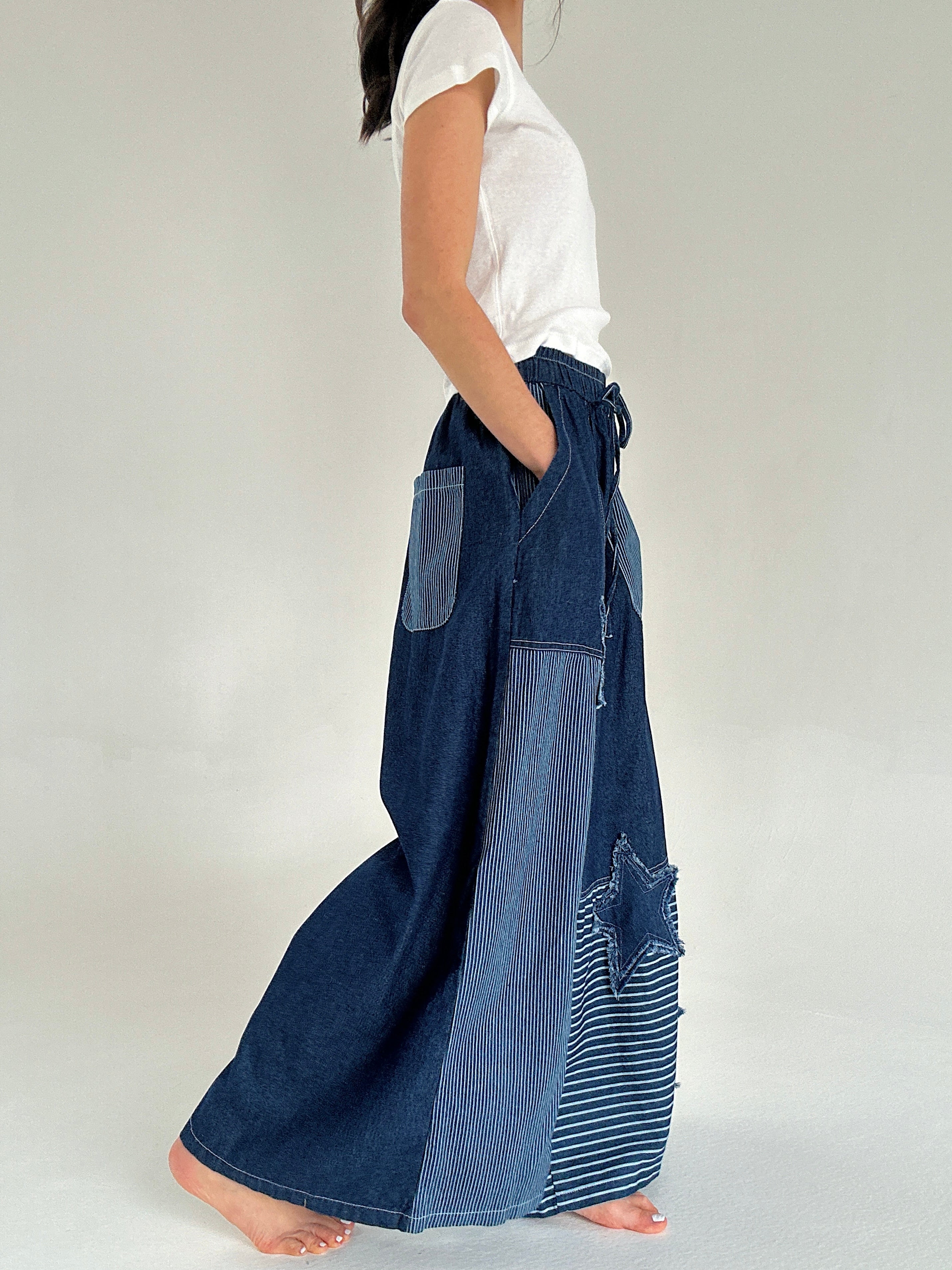 Person wearing a pair of blue denim pants with a white background from side