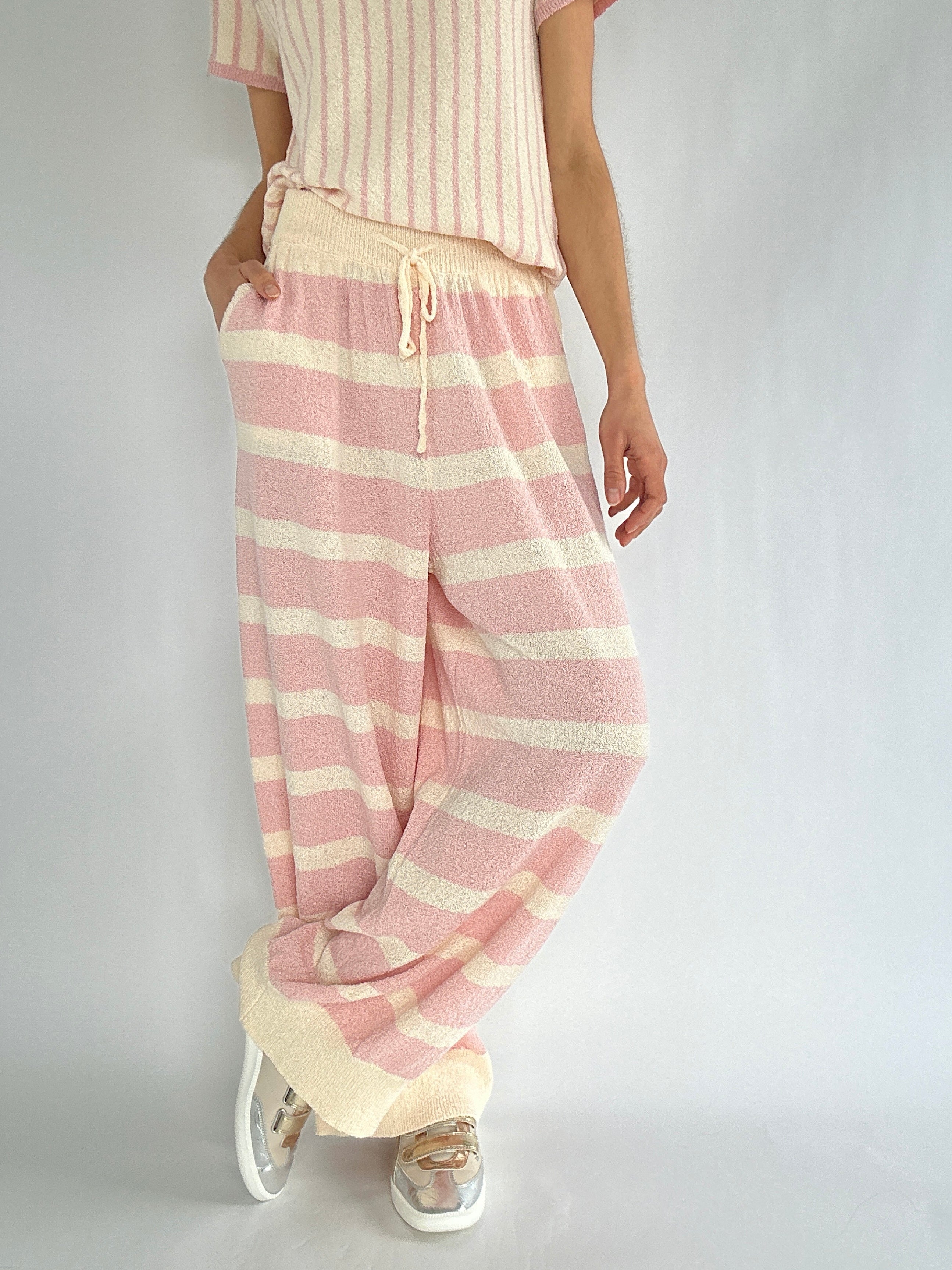 Person wearing pink and cream striped pants with a plain background