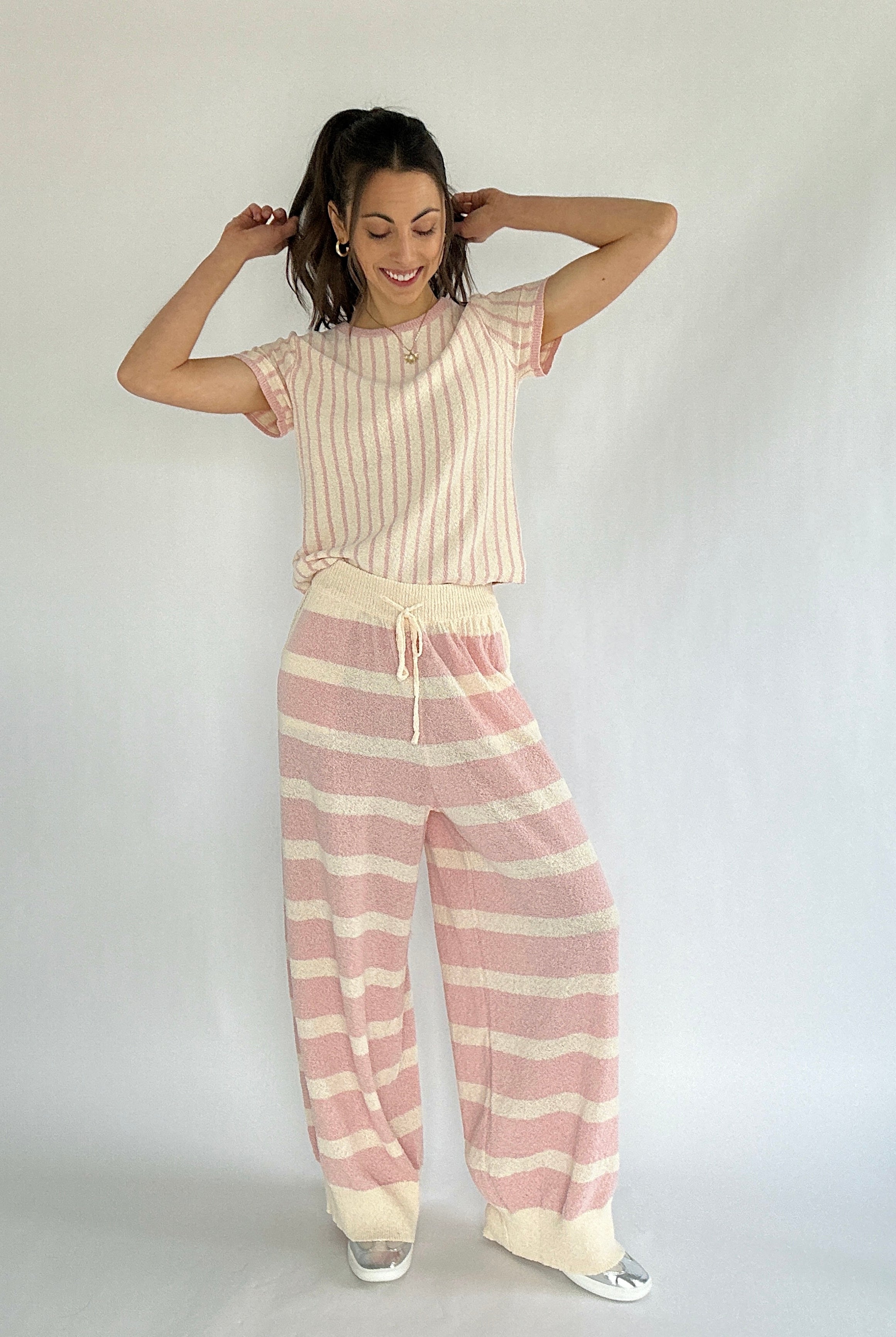 Woman wearing a pink and cream striped top with coordinating striped pants against a white background