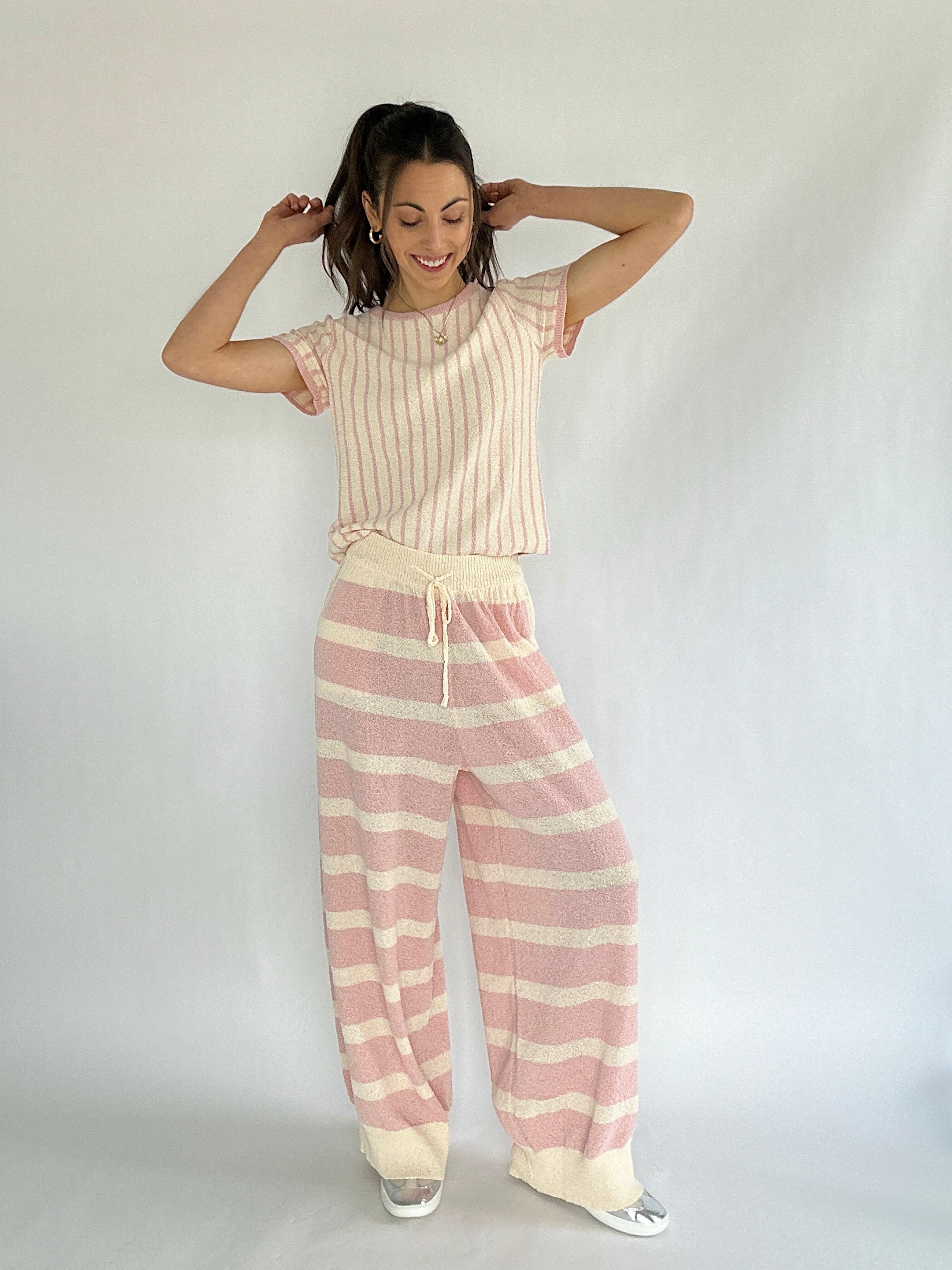 Woman wearing a pink and cream striped top with coordinating striped pants against a white background