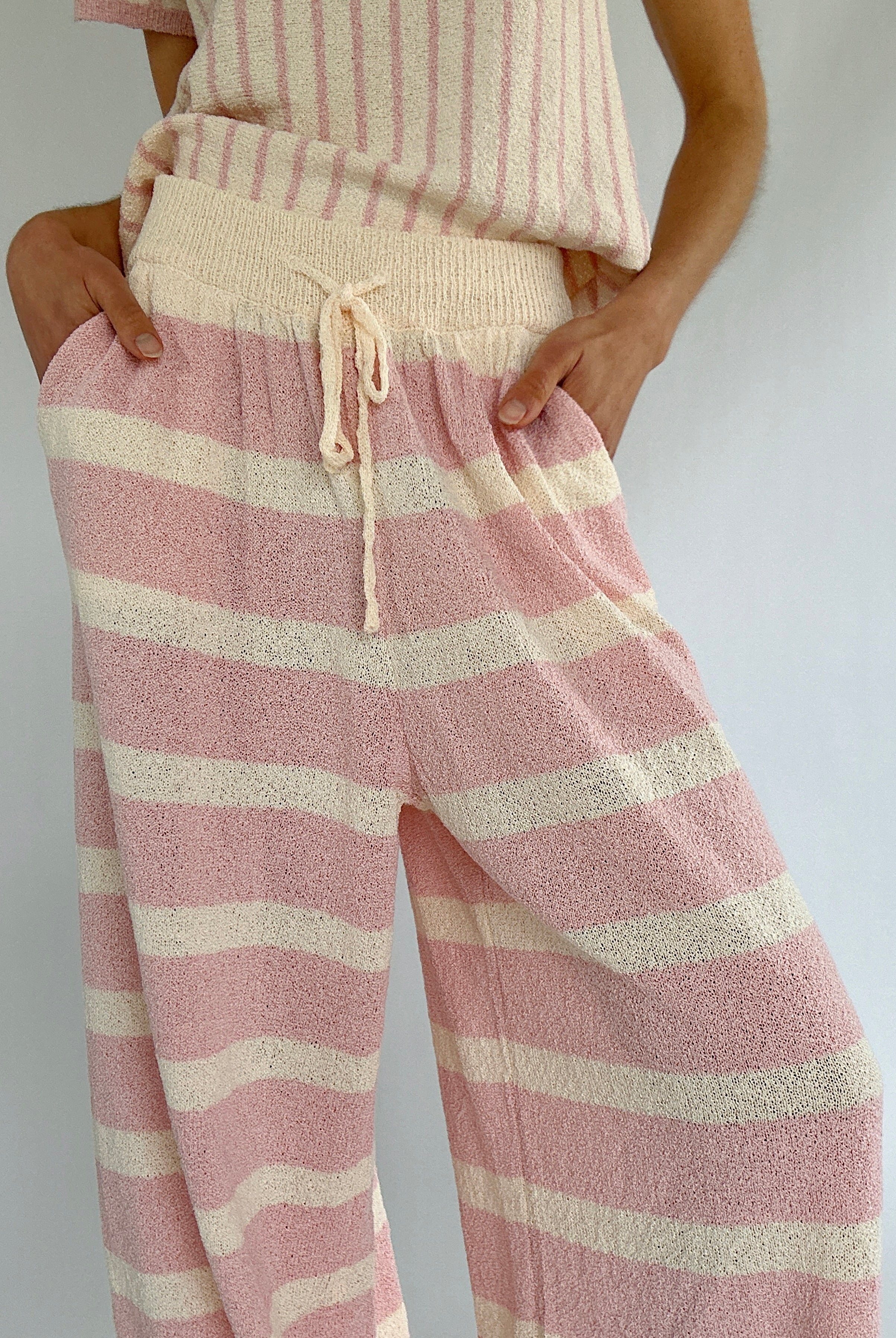 Pink and cream striped pants worn by a person on a plain background