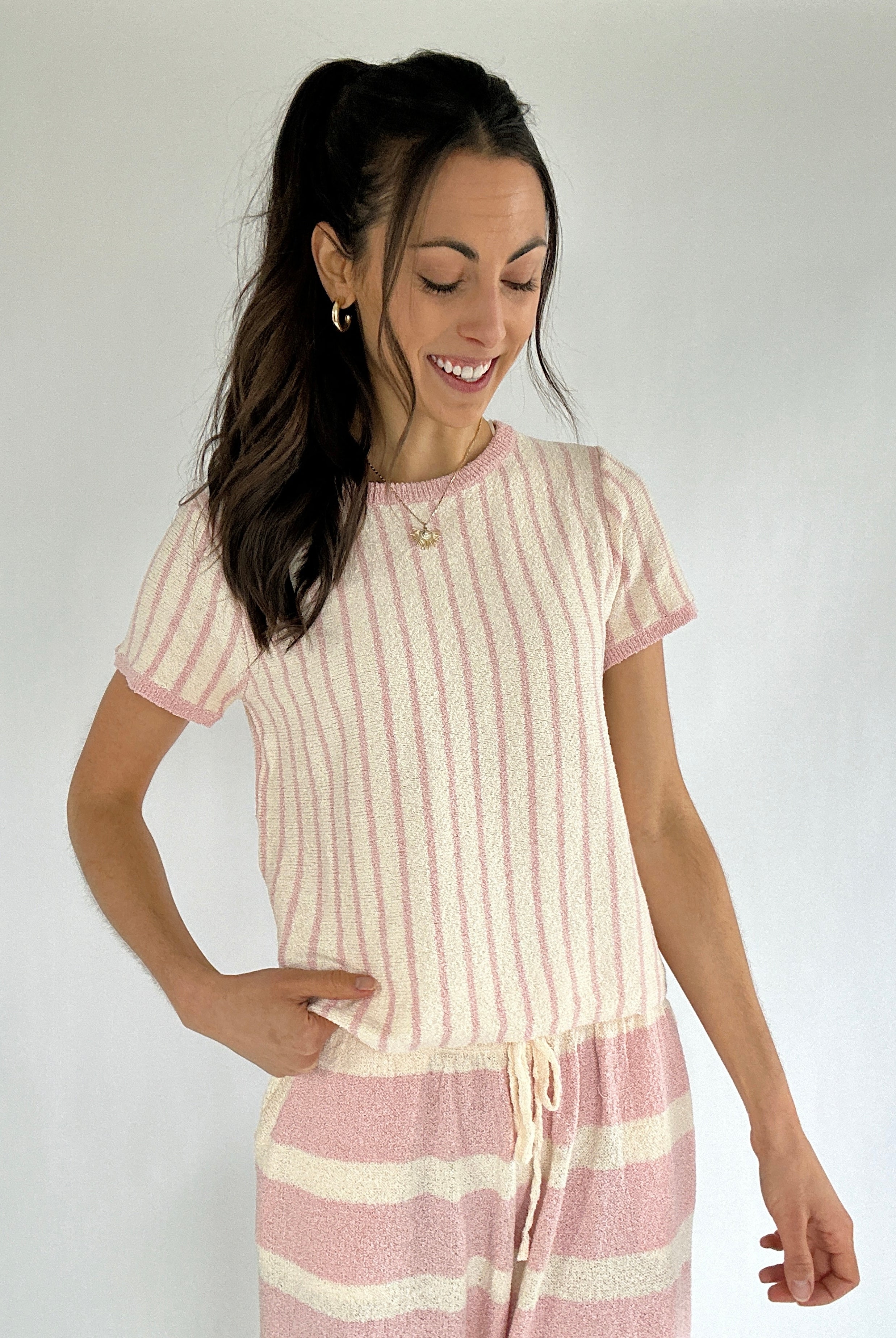 Woman wearing a pink and white striped outfit against a plain background