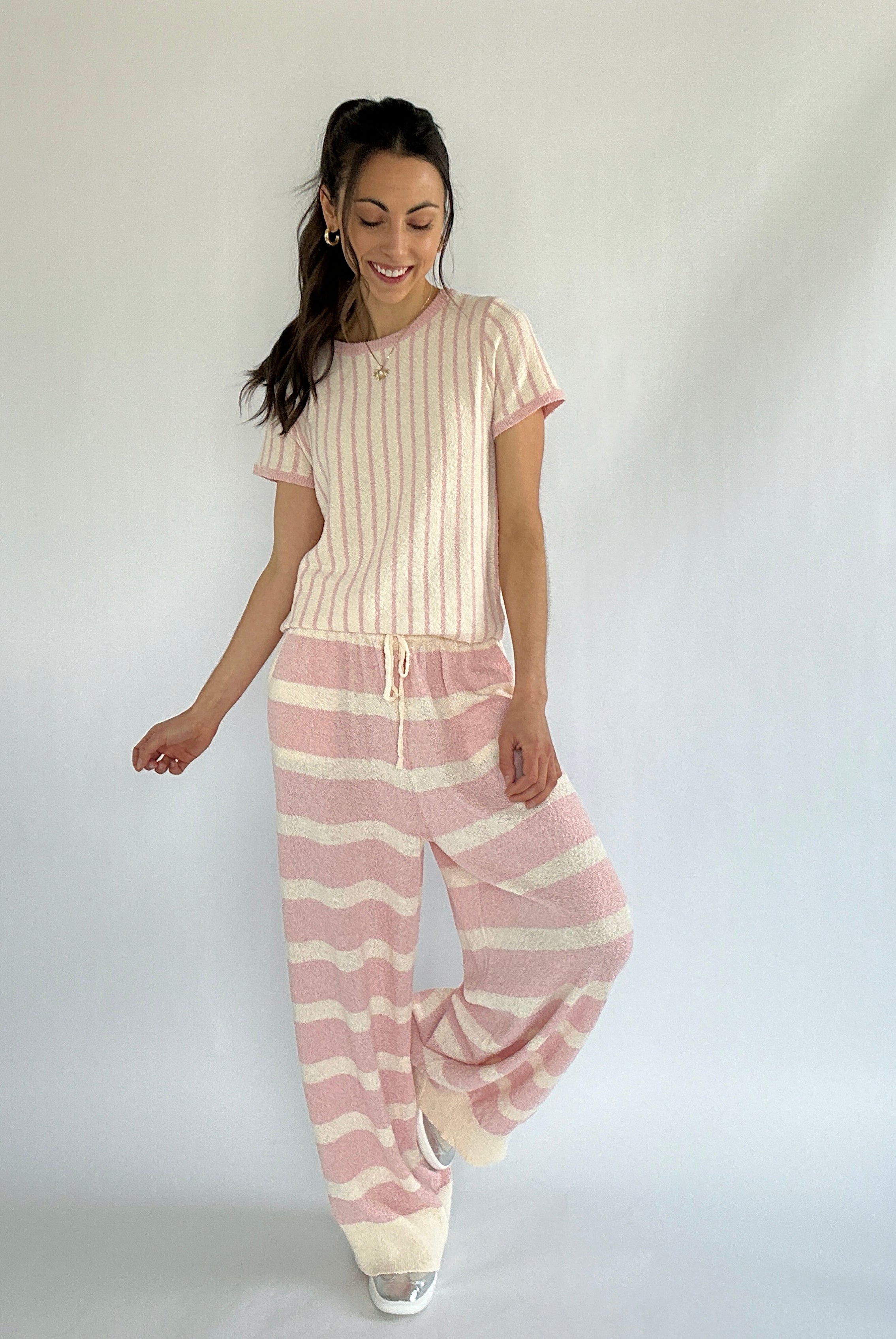 Woman wearing a pink and white striped outfit on a plain background