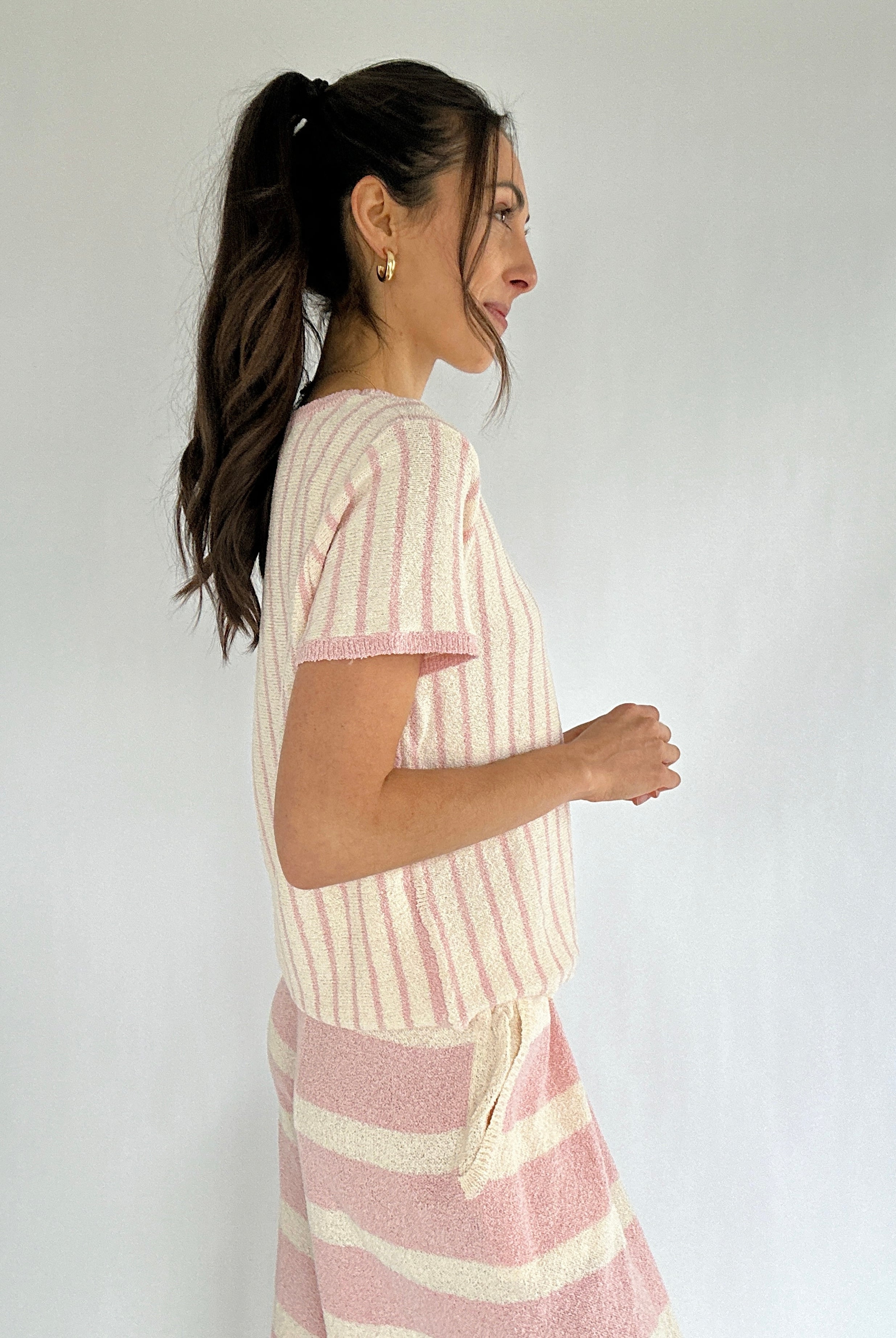 Woman wearing a pink and white striped outfit against a plain background