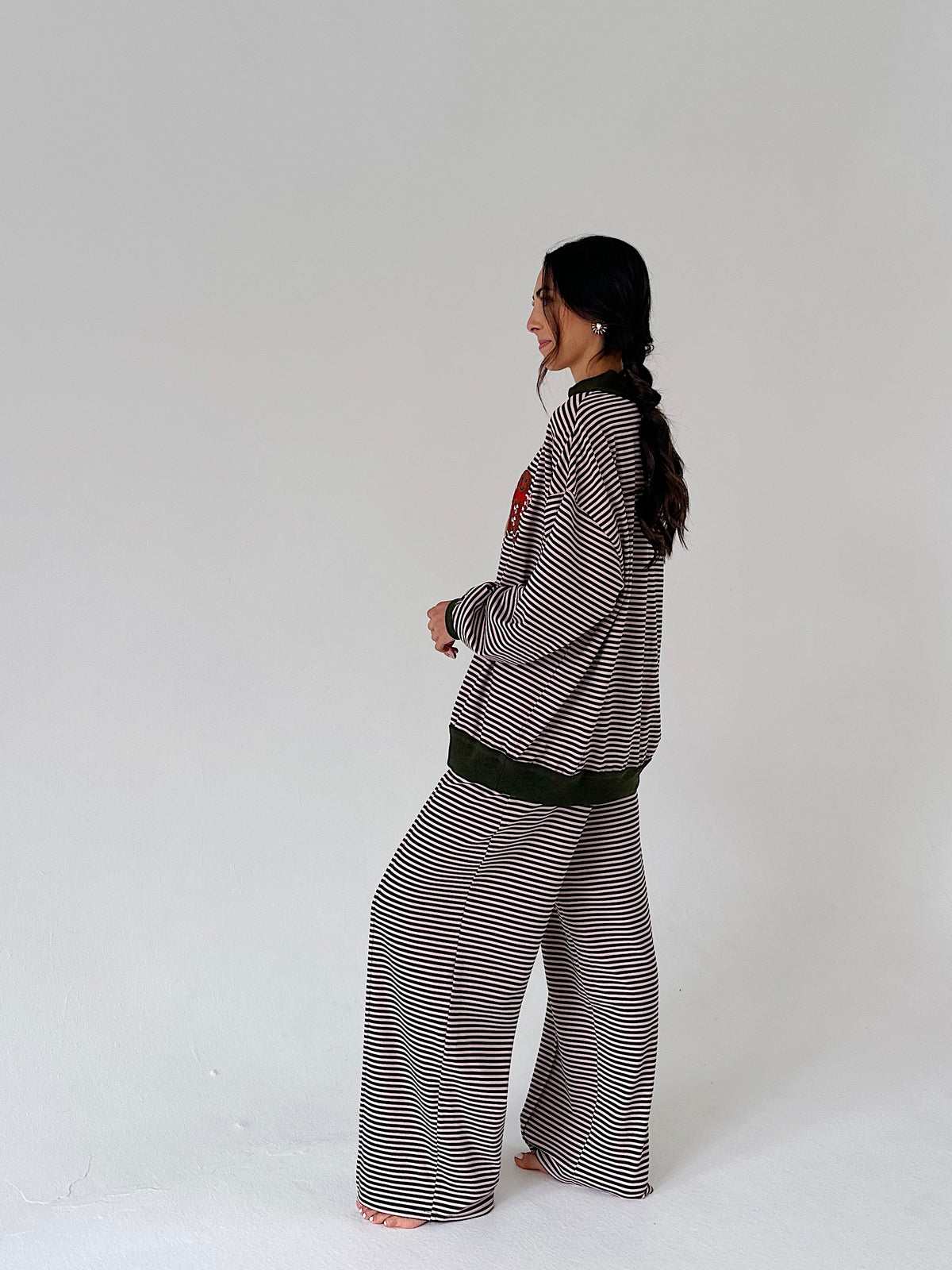 A woman modeling a matching two-piece loungewear set consisting of a long-sleeve top and wide-leg pants, both featuring a black and white horizontal stripe pattern with solid black ribbed trim.