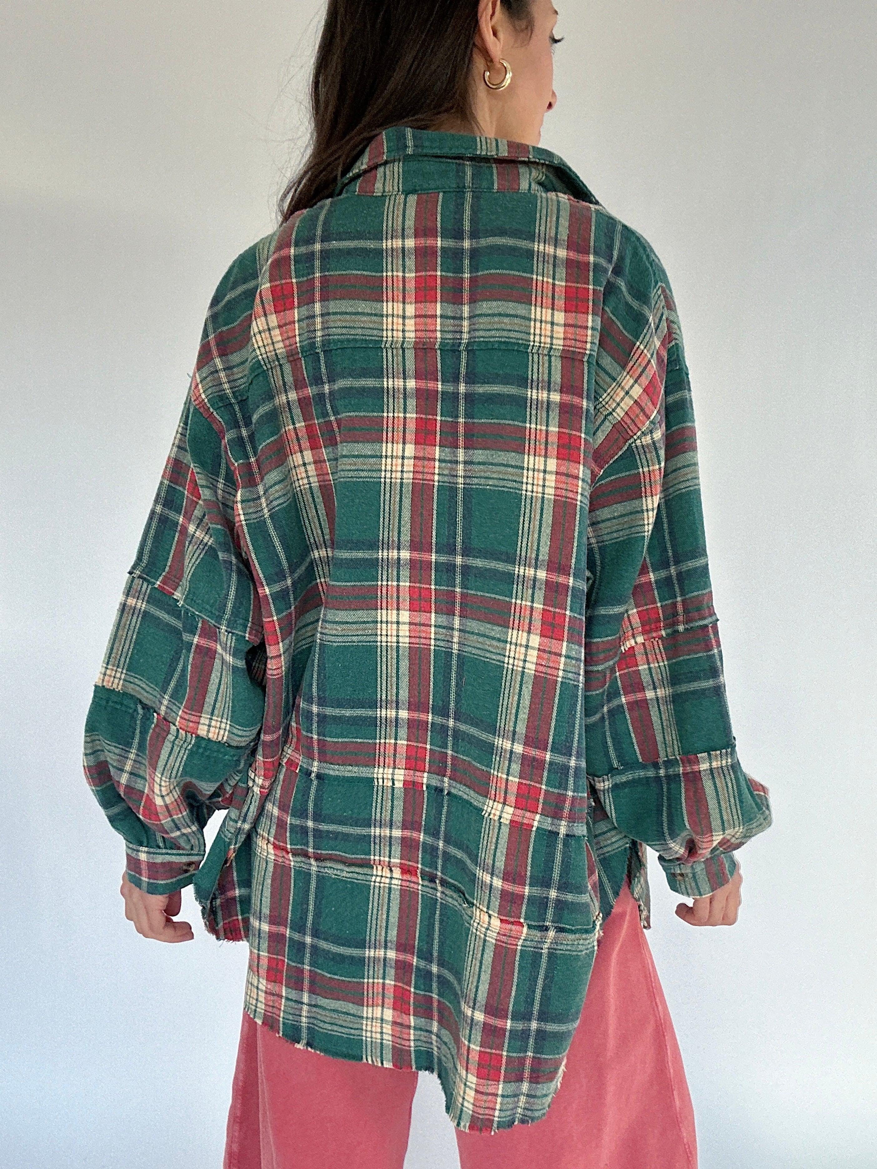 Person wearing a green plaid shirt with a white background showing back