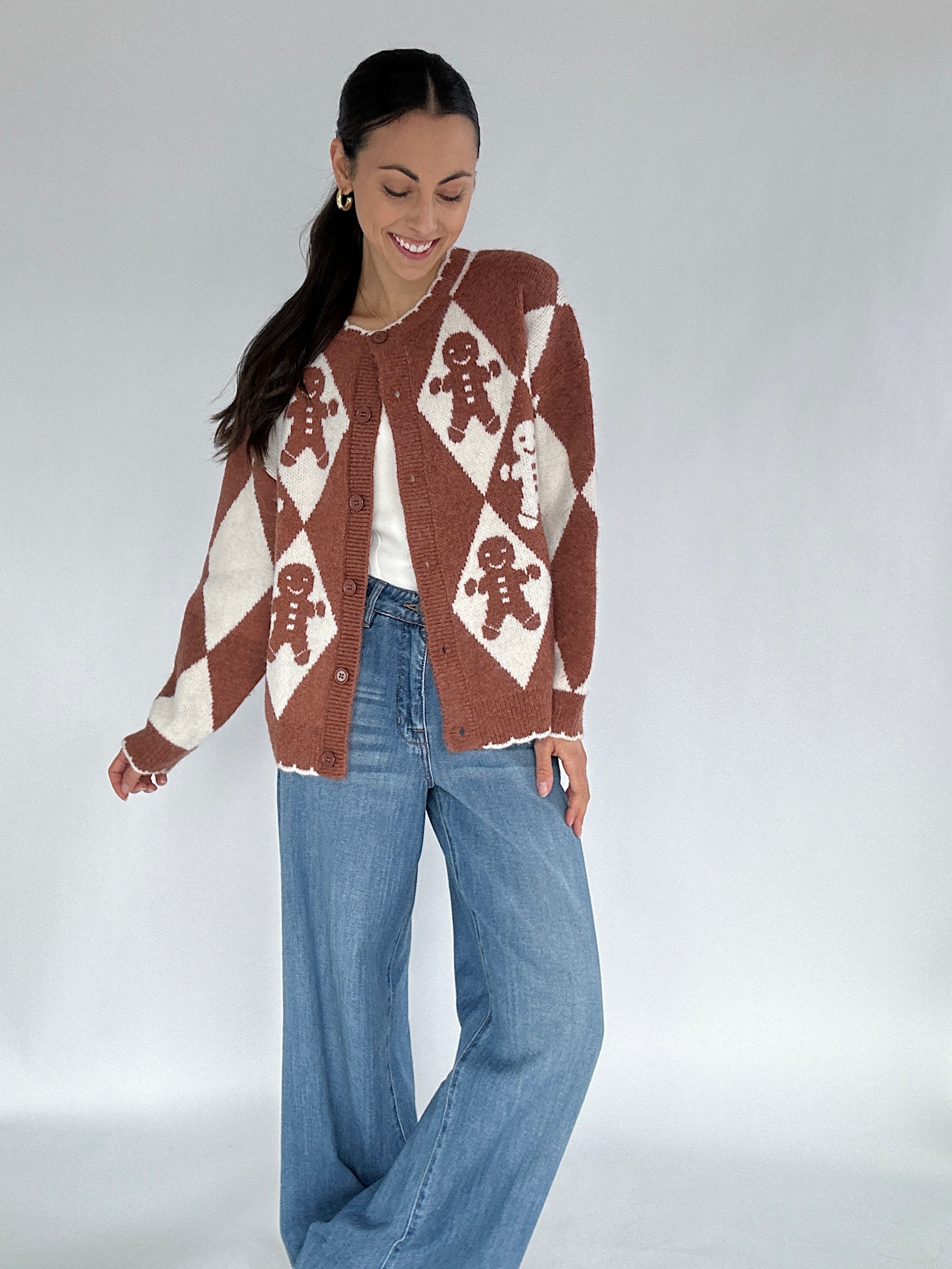 Woman wearing a gingerbread-themed cardigan on a plain background