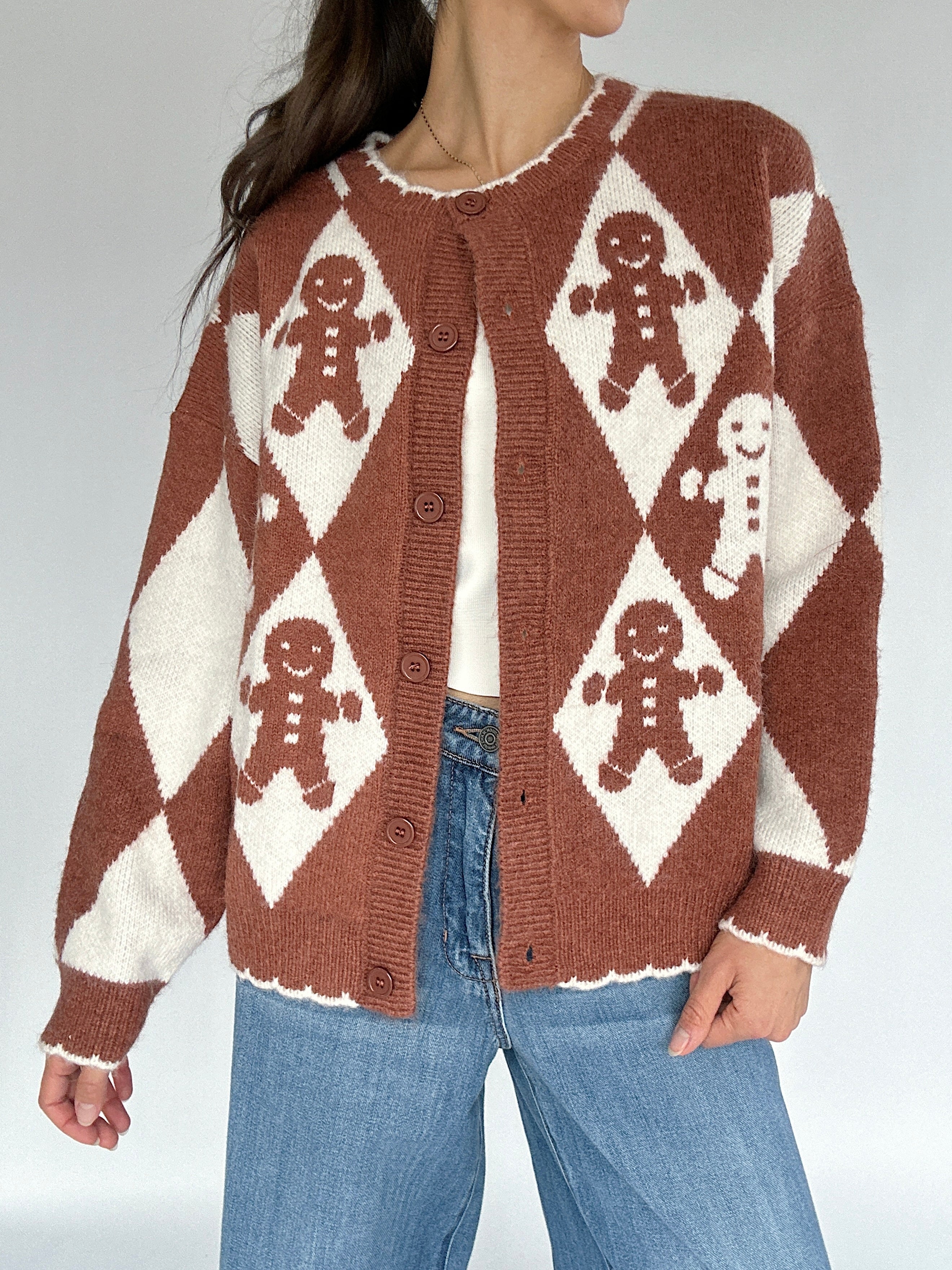 Person wearing a brown and white patterned sweater with gingerbread men design.