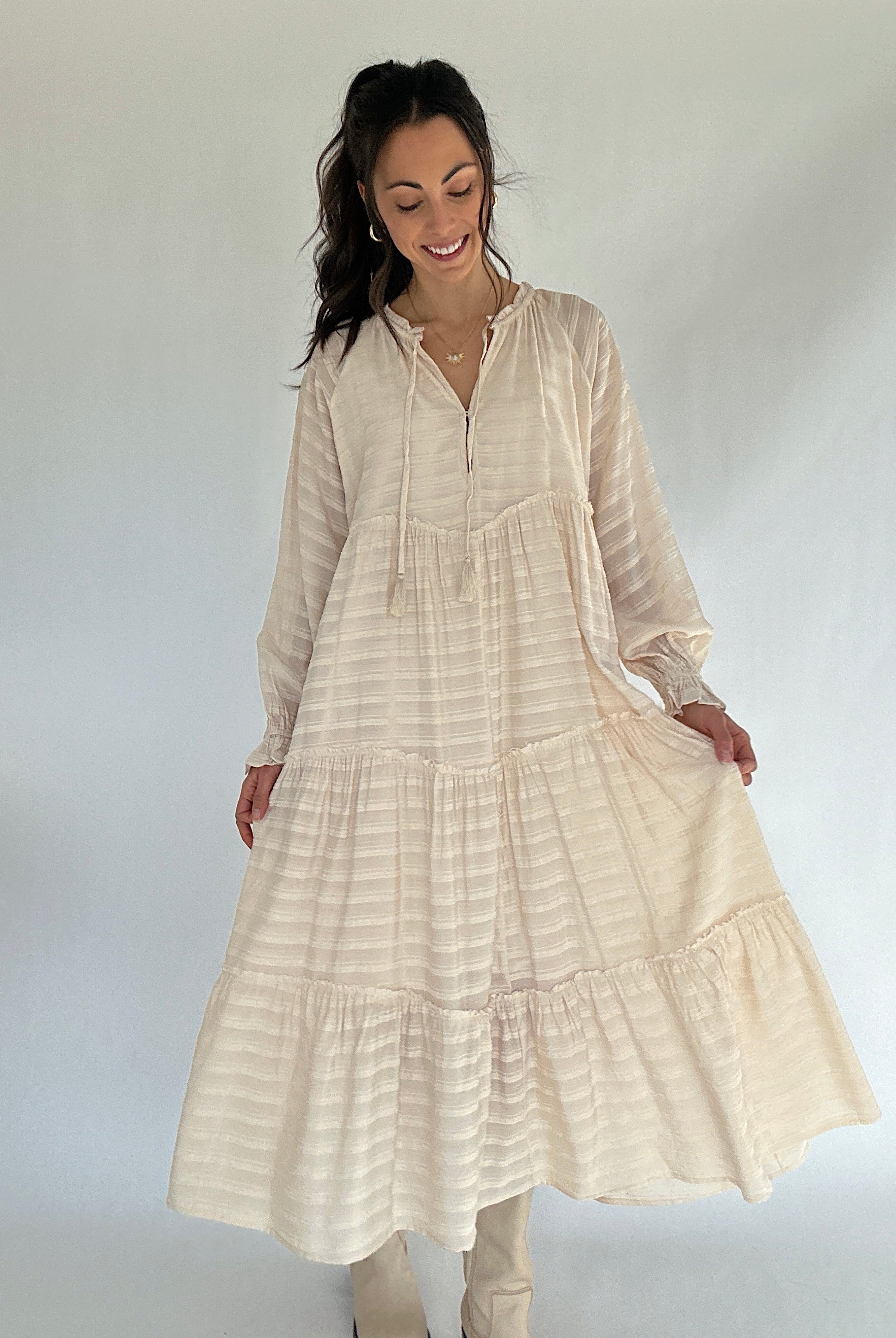 Woman wearing a beige long dress with a white background