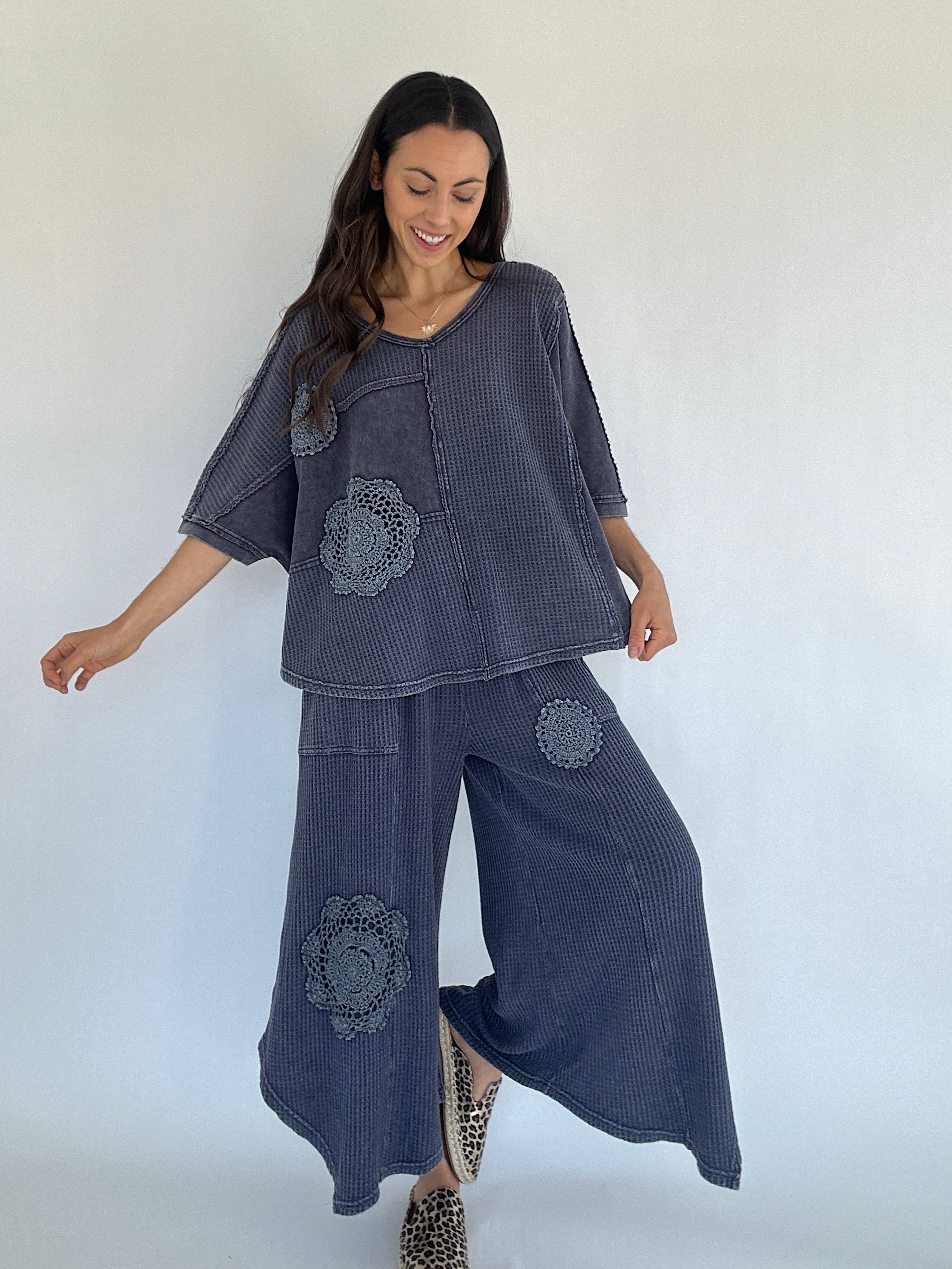 Woman wearing a dark blue waffle knit outfit with floral patches on a white background