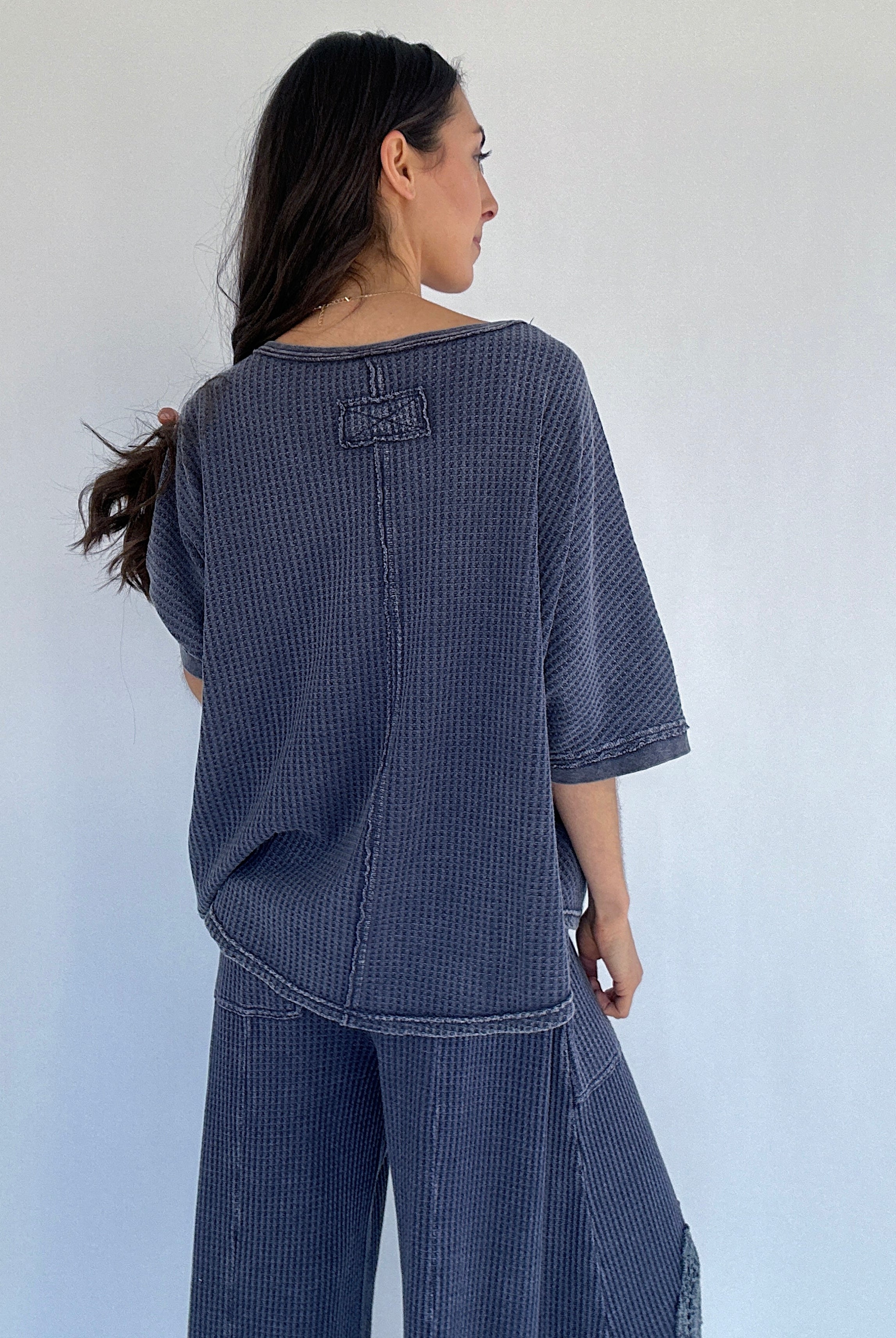 Person wearing a blue textured outfit against a white background showing the back