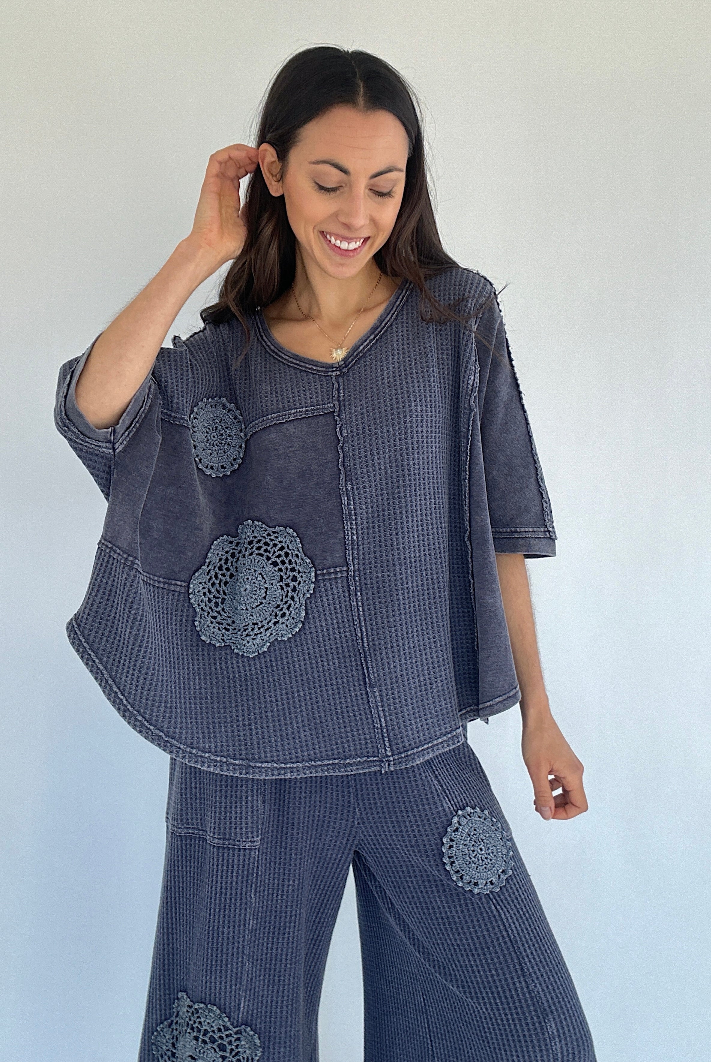 Woman wearing a midnight blue textured outfit with floral patterns against a white background