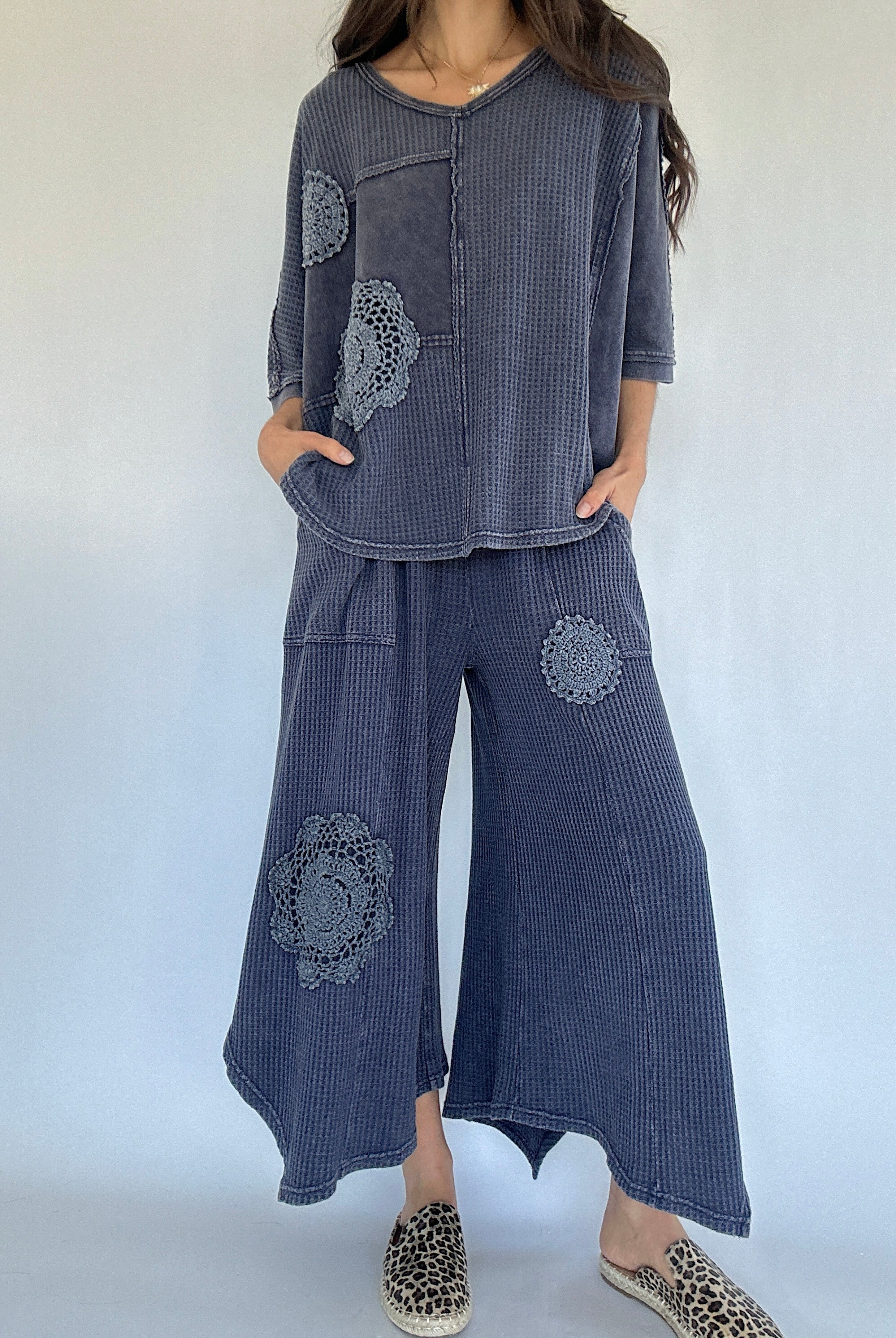 Person wearing a blue textured outfit with floral patterns on a white background